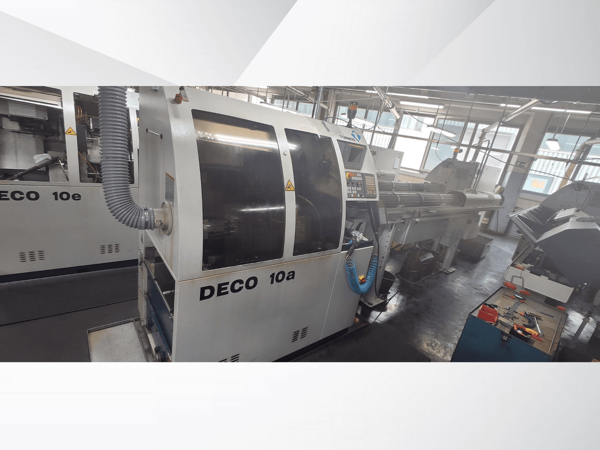 DECO 10a CNC machine in a workshop, showing front view, control panel, and exhaust system. Features robust build and precision tools.
