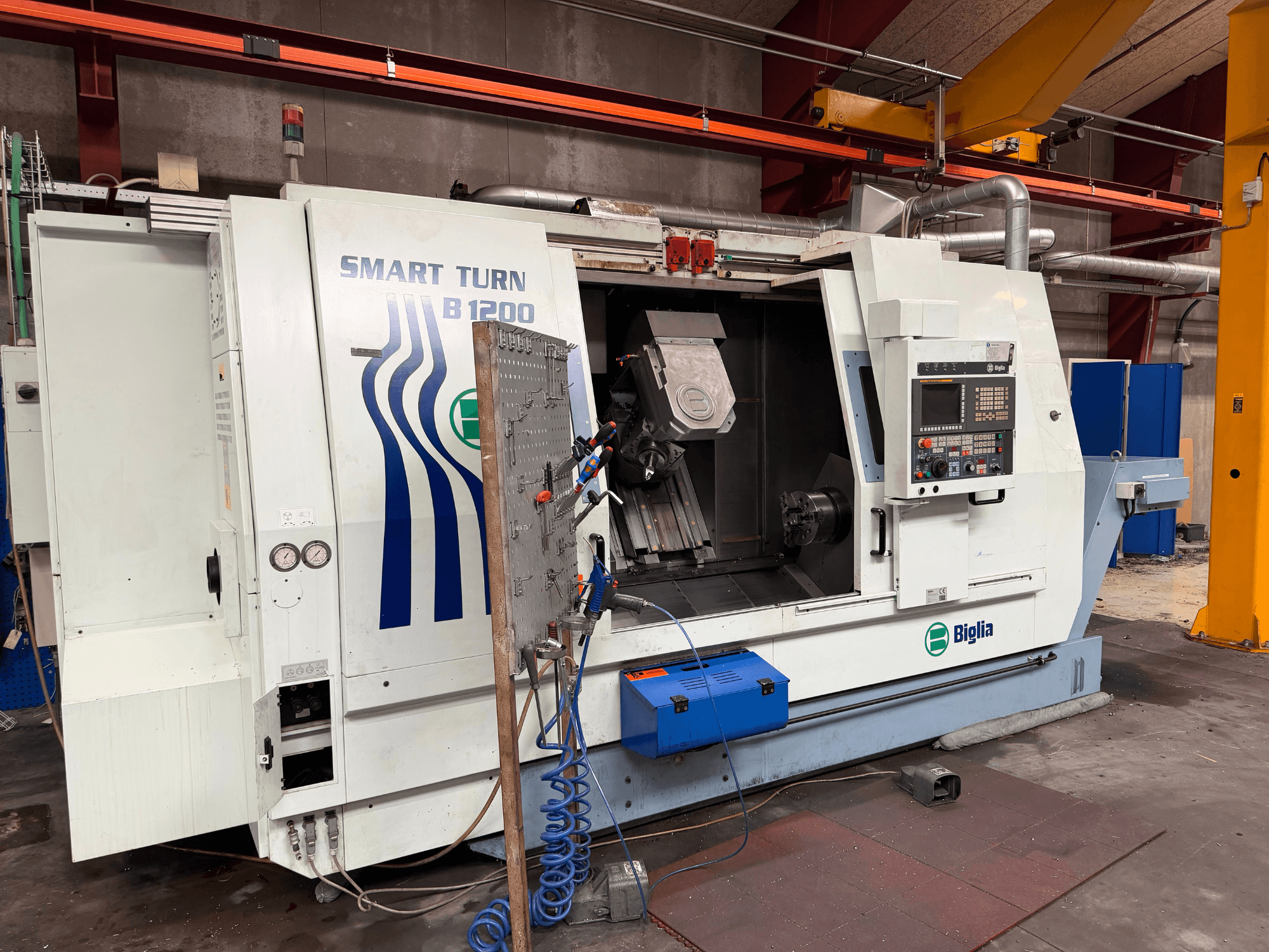 Biglia B.1200/S-Smart turn-mill centre in front view; features controls, a workpiece in the spindle, and pressure gauges.