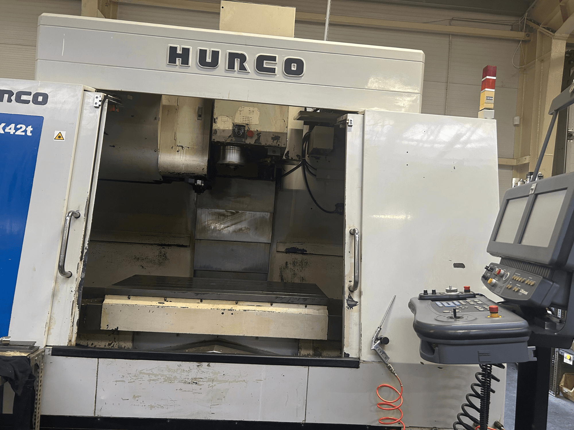 Hurco VMX42T CNC milling machine in front view, featuring an open workspace and control panel with buttons and display.