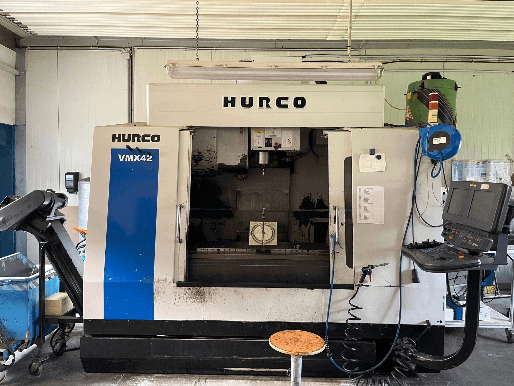 Hurco VMX 42 vertical machining center in side view, showing control panel, spindle, and workpiece setup.