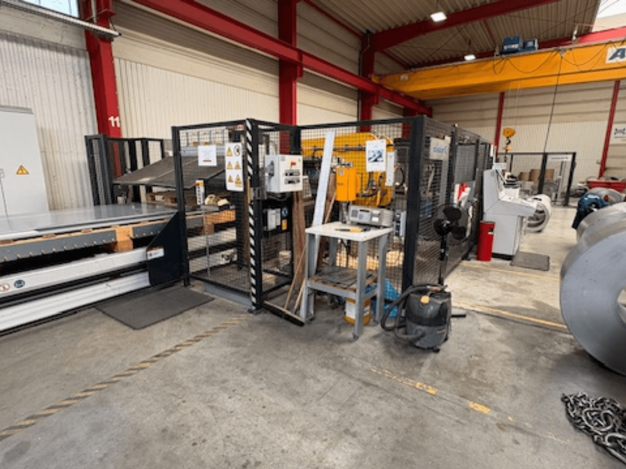 Sheet metal machine by SCHULER, model AC-PLS-1600-M, in a workshop, side view showing safety enclosure and adjacent equipment.