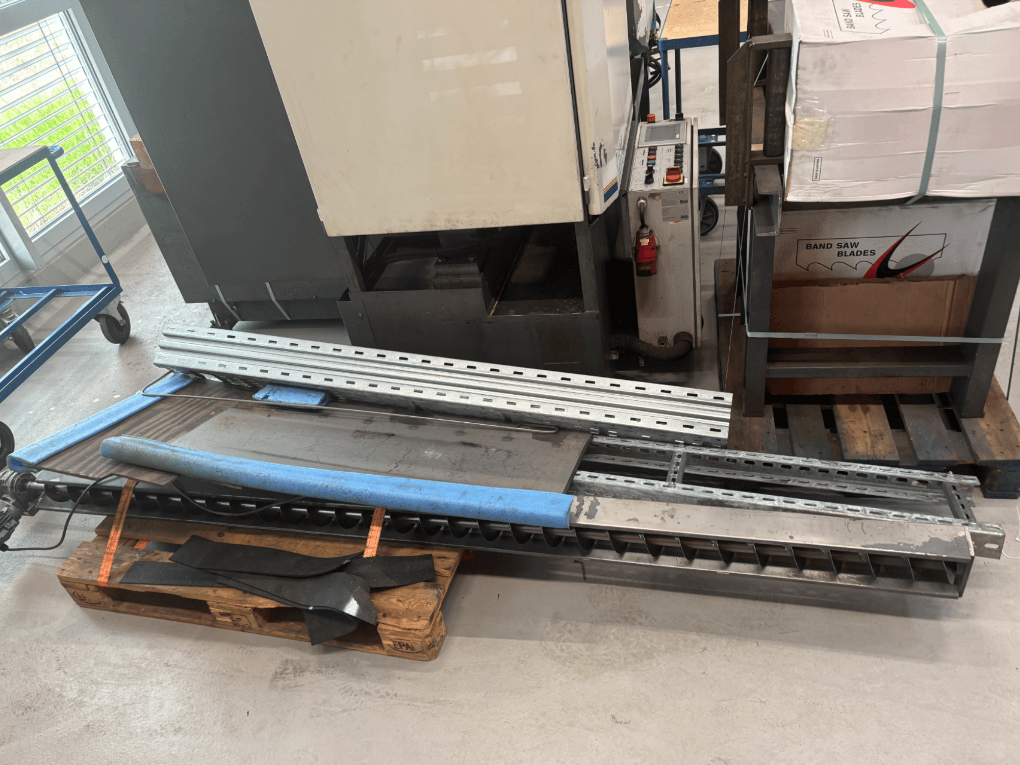 BAUER SA 430 ZA metal band saw displayed from the side, with metal frame and components on a wooden pallet.