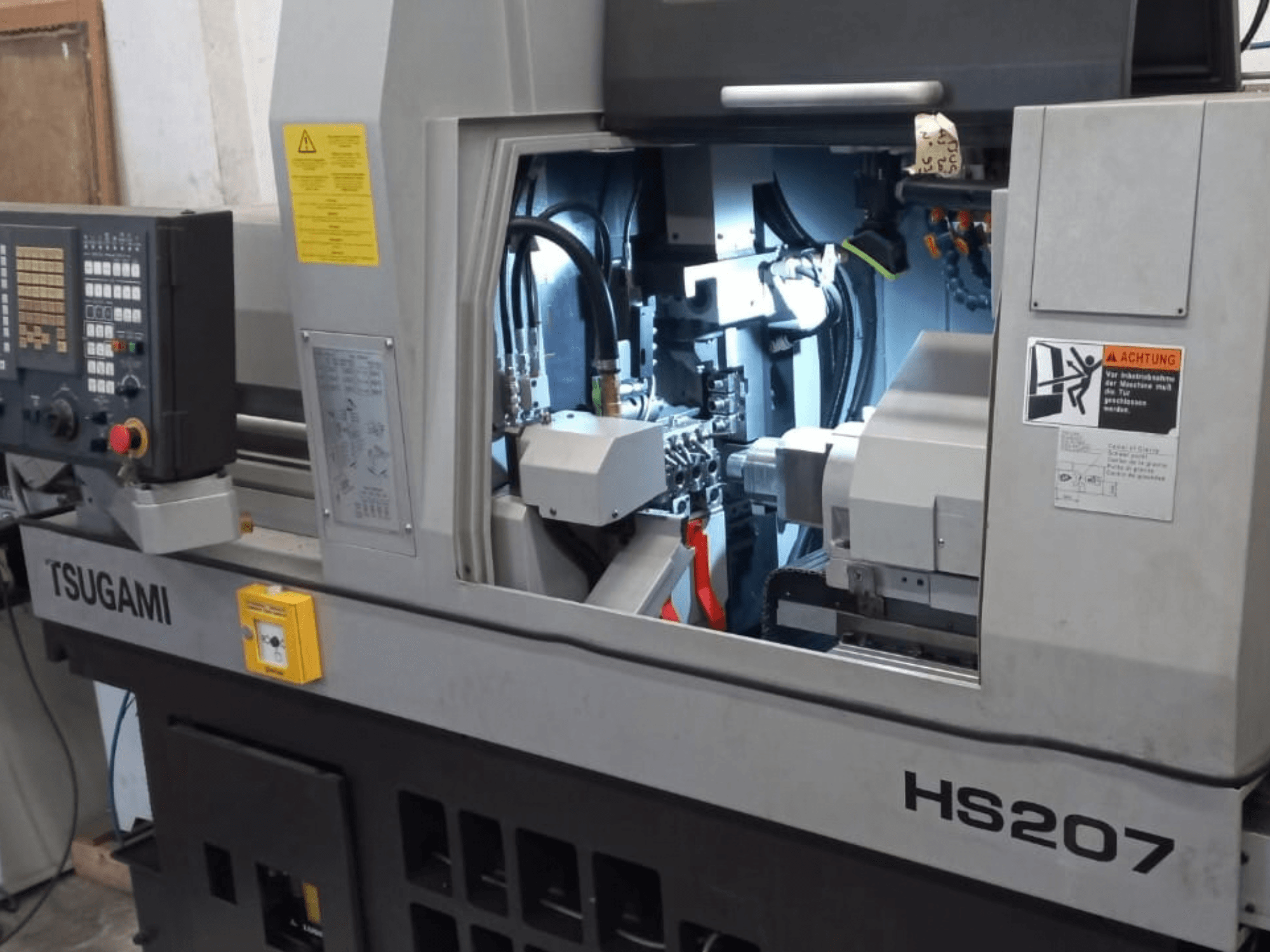 TSUGAMI HS207 Swiss type turning machine, front view showing control panel and internal components.
