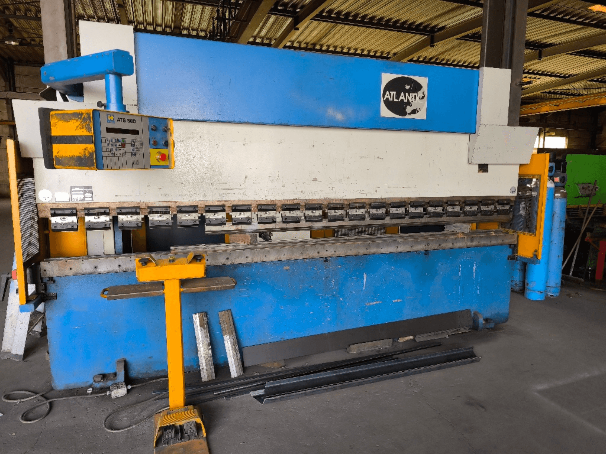 Front view of ATLANTIC HPES-40-135 press brake, featuring control panel, bending tools, and metal workpieces beside it.