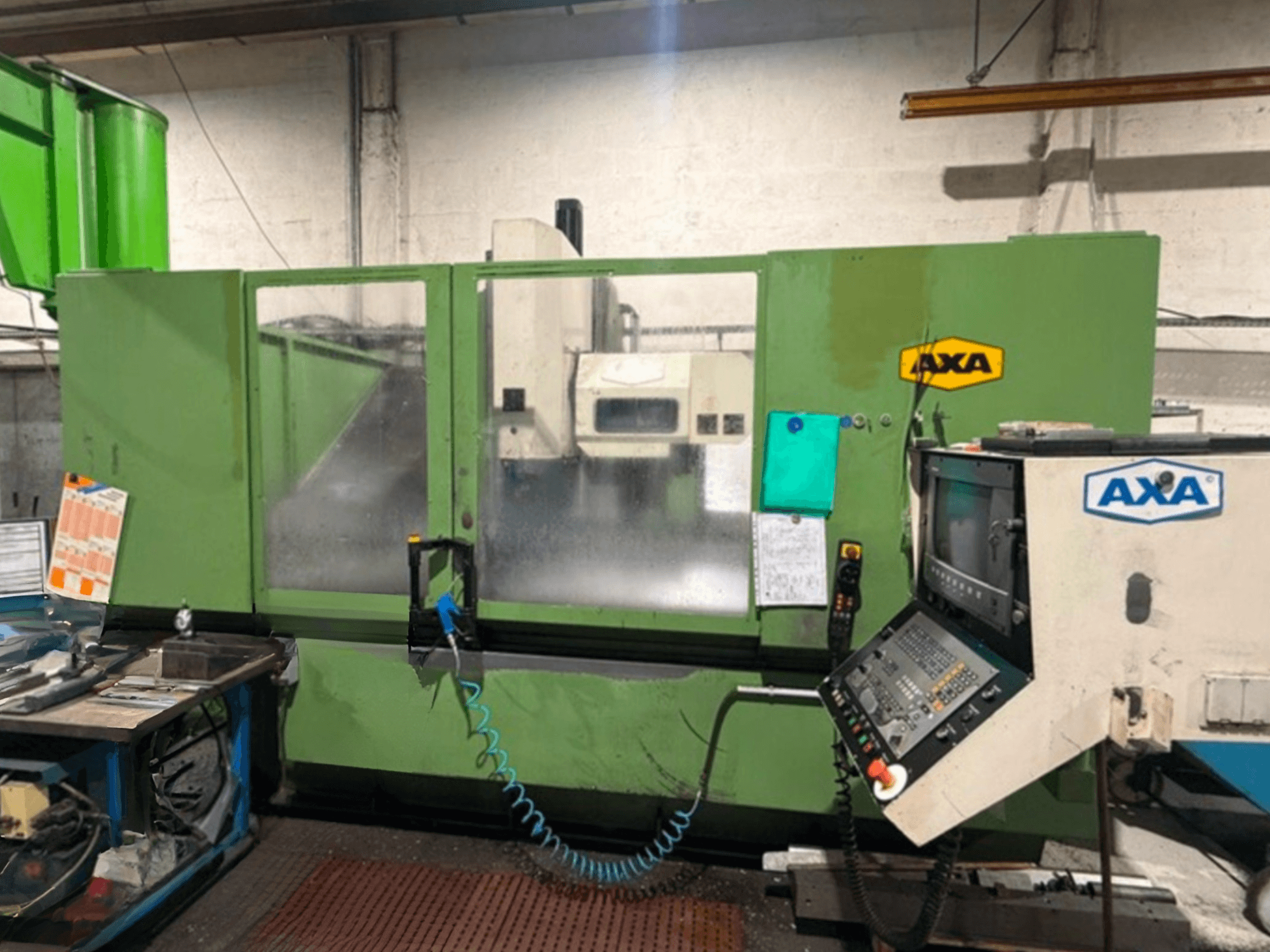 AXA Vario vertical machining centre in green, front view, with control panel and details visible, set in a workshop environment.