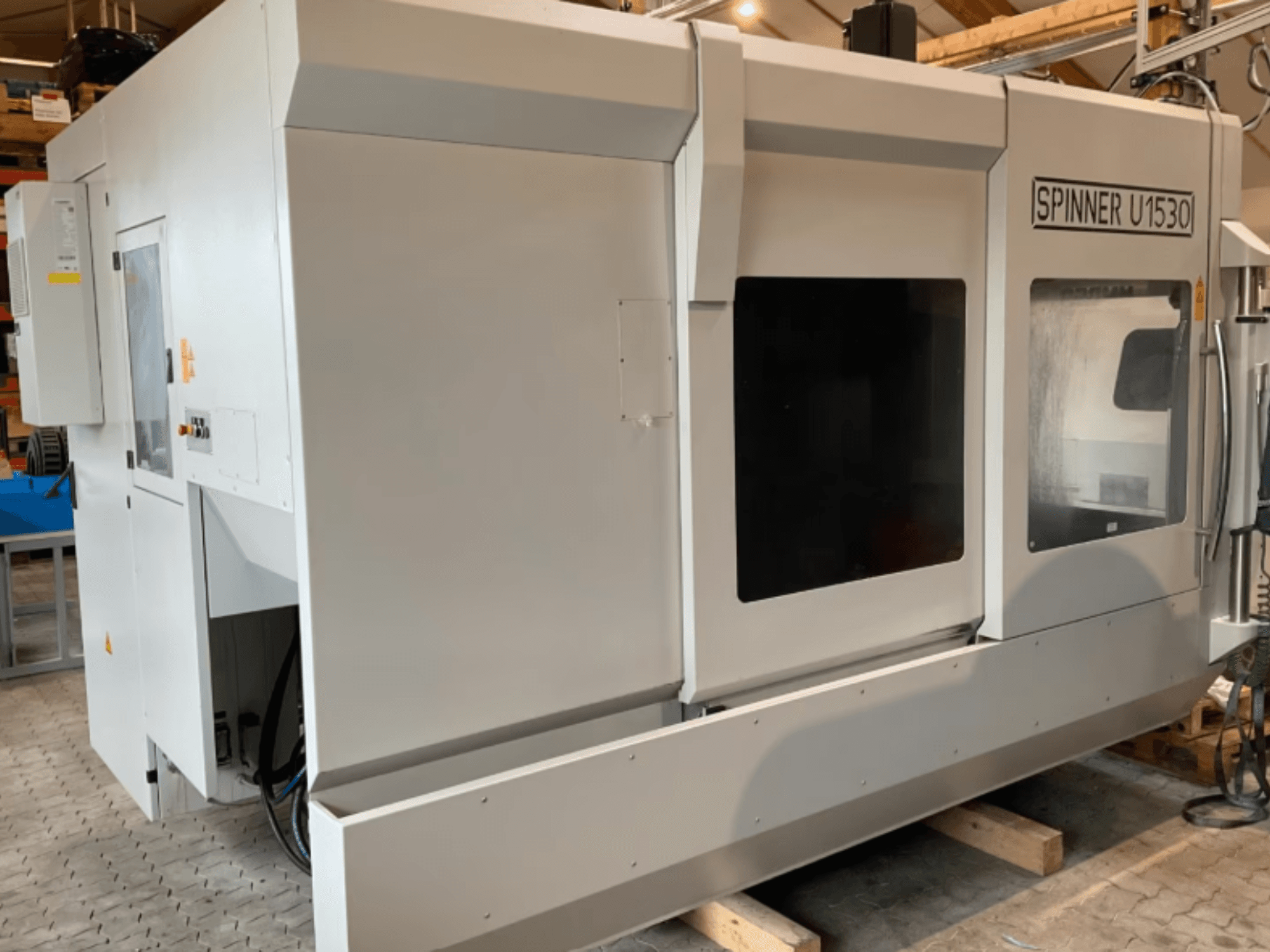 Vertical machining center SPINNER U5-1530 shown in a side view, featuring a large working area and control panel.