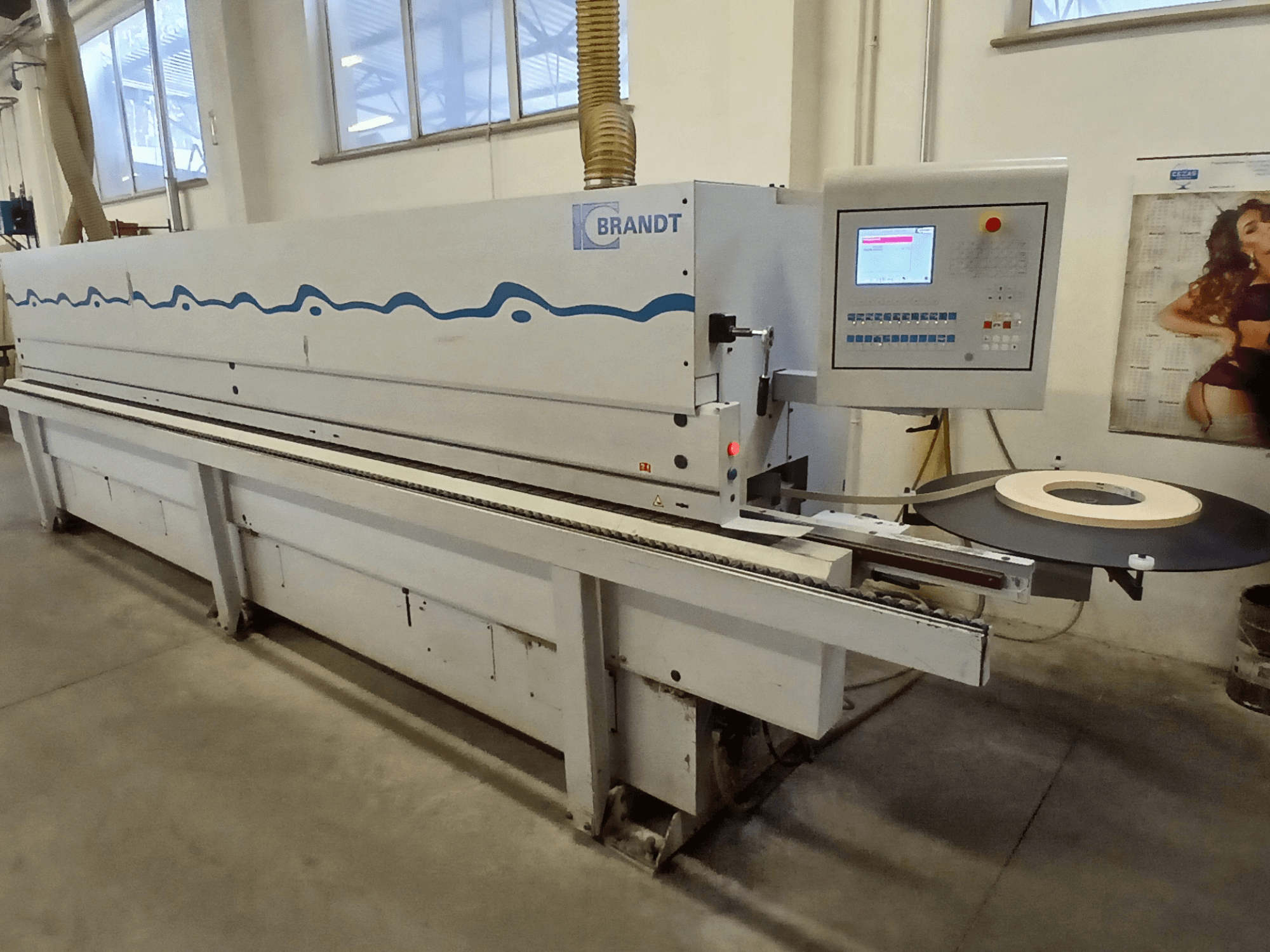 Brandt edge banding machine, side view, featuring a control panel and a roll of tape on the feeding table.