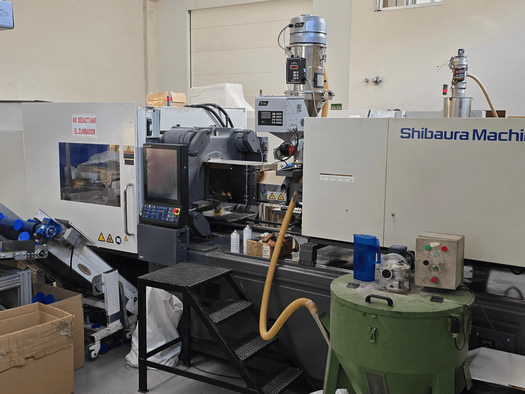 Front view of SHIBAURA EC230SXIII-8A electrical injection molding machine with control panel and adjacent equipment.
