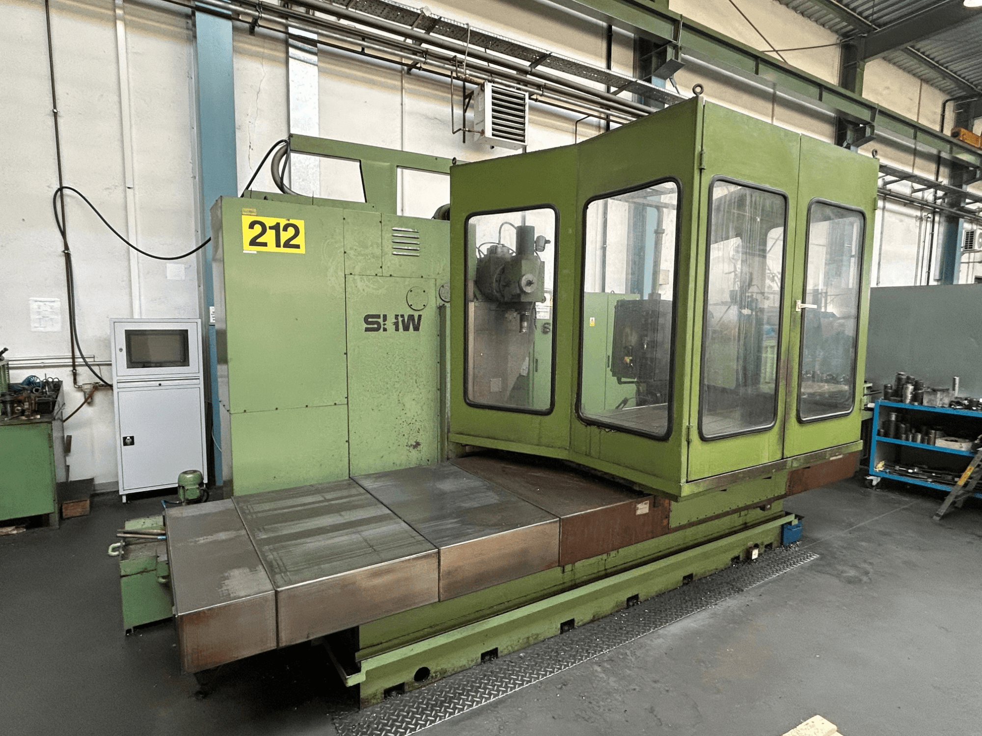 SHW UF-5 vertical machining center in green, front view showing control panel, glass enclosure, and metal worktable.