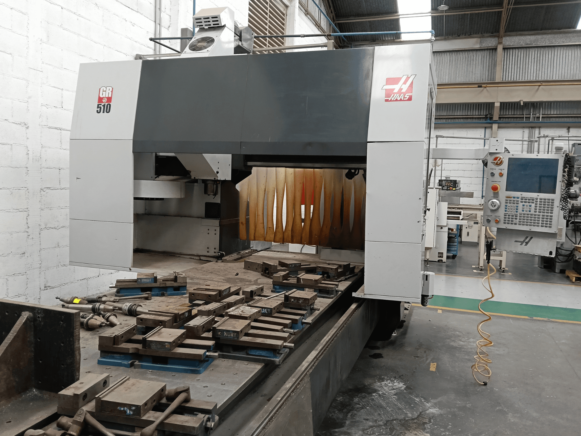 Front view of HAAS GR-510 gantry milling machine, showcasing control panel and machined workpieces on the table.