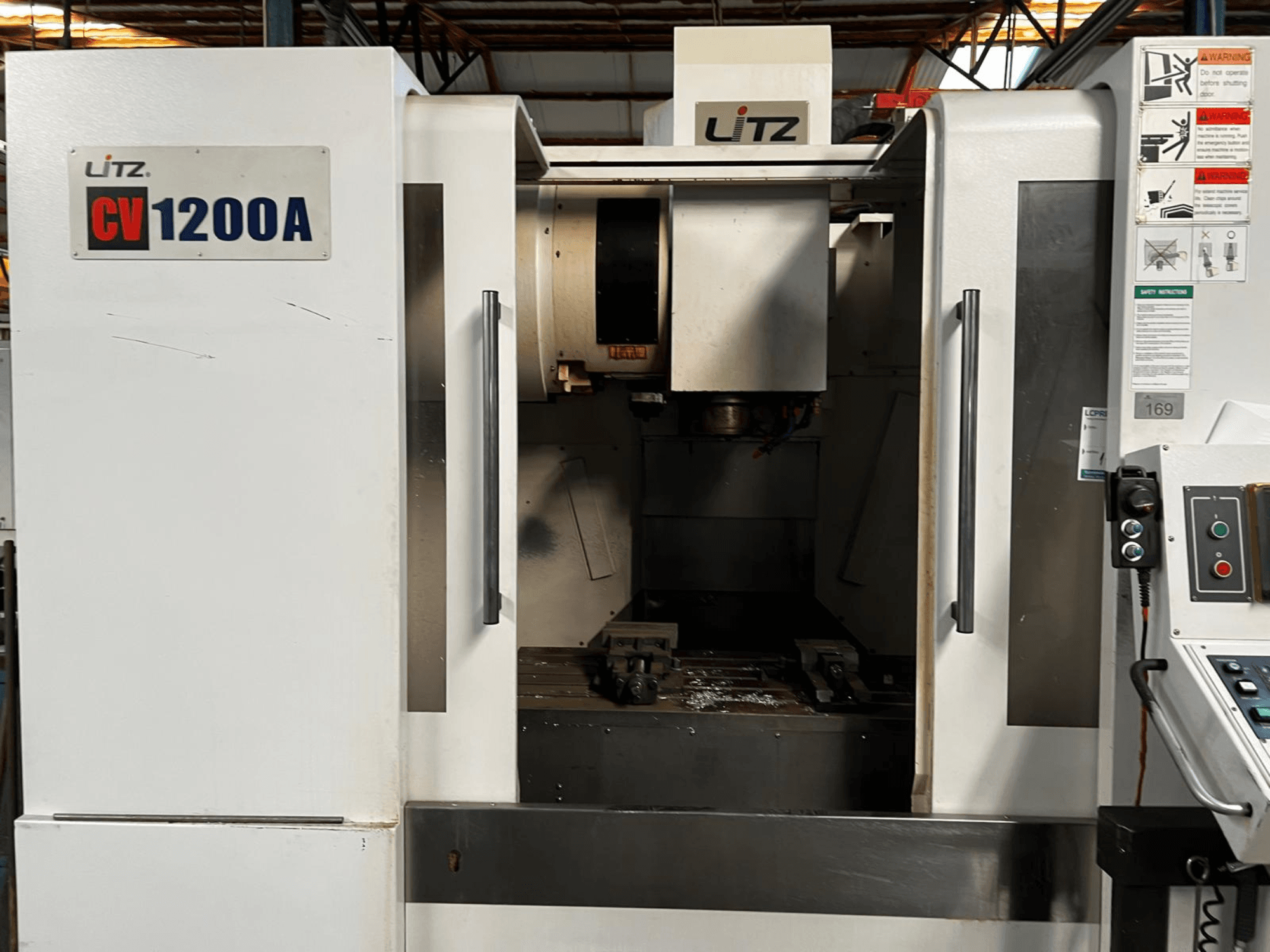 Litz CV1200A vertical machining center, front view, showing control panel, spindle, and open door revealing work area.