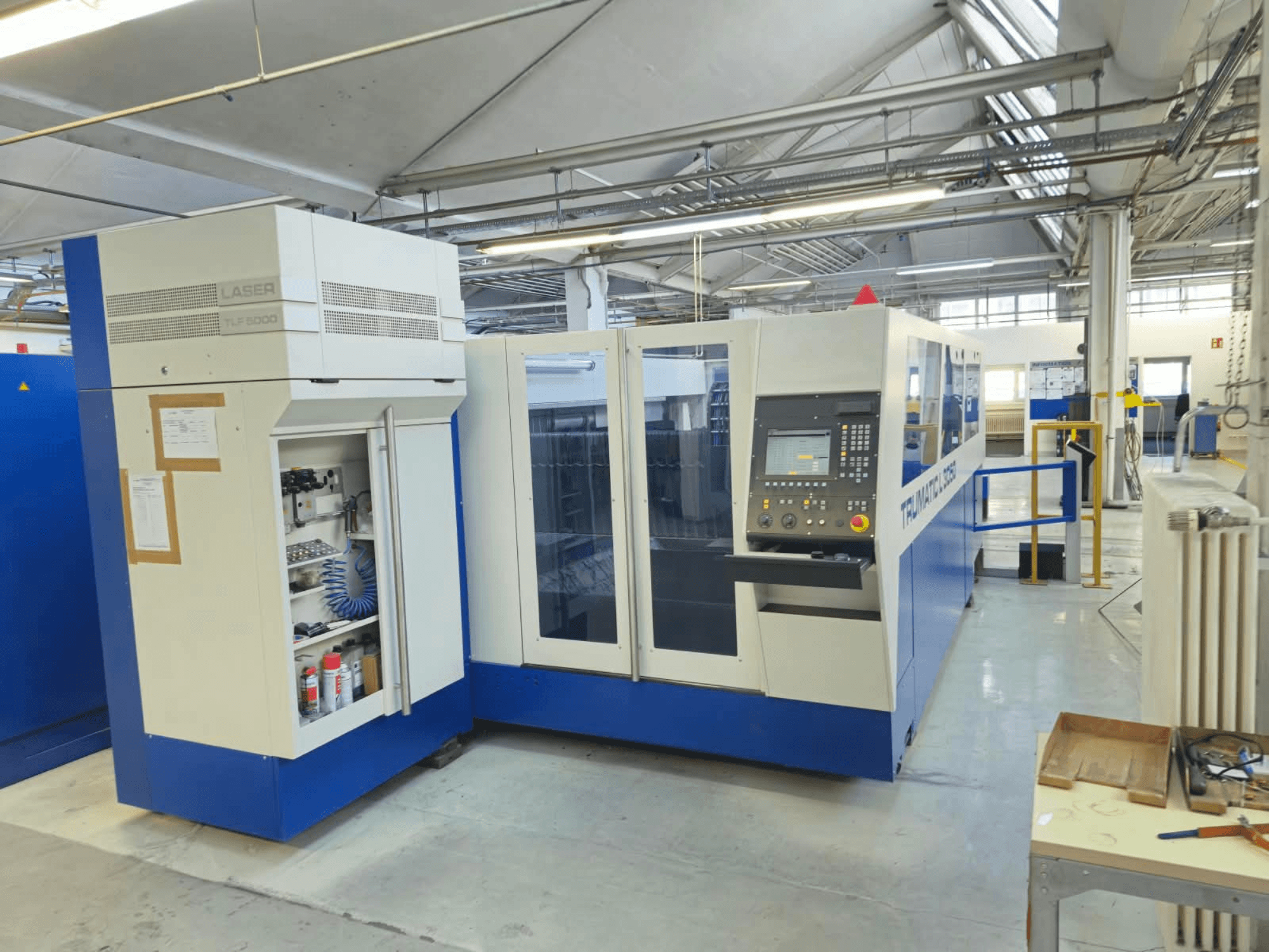 TRUMPF TruLaser L3050 CO2 laser cutting machine, front view, featuring control panel and maintenance access door, in a factory setting.
