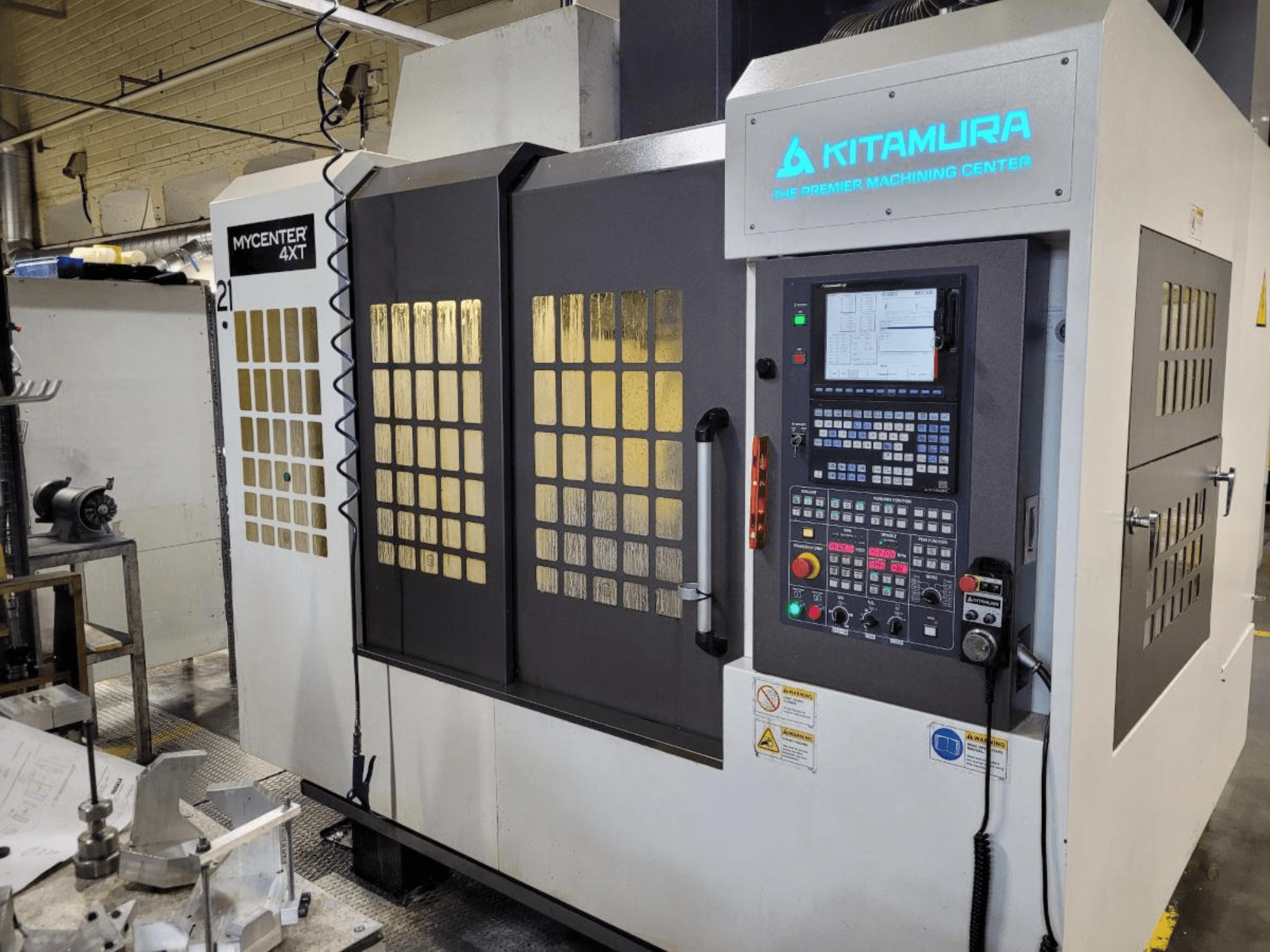 Vertical view of a Kitamura Mycenter-4XT machining center, featuring a control panel and illuminated branding.