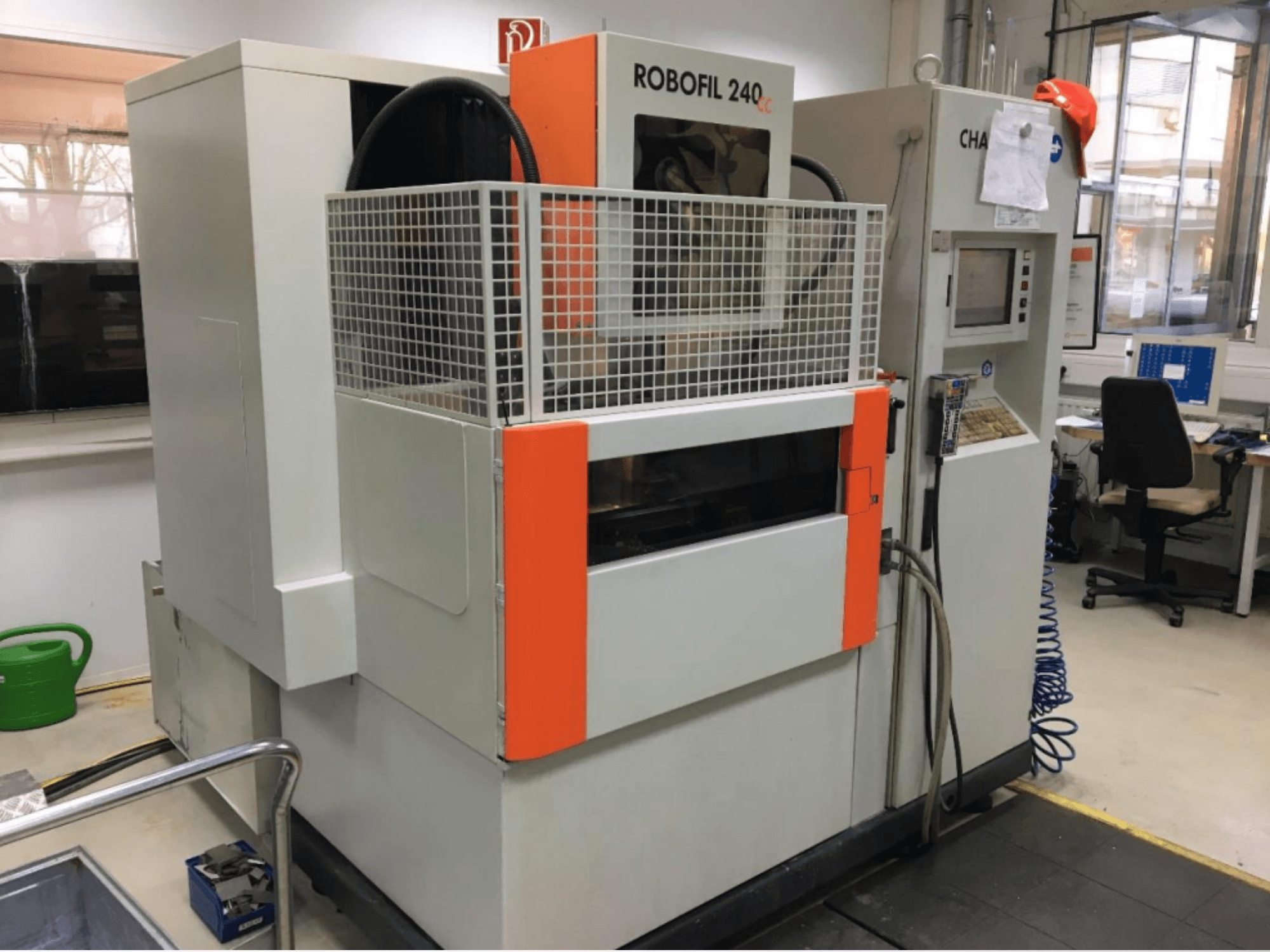 Front view of CHARMILLES ROBOFIL 240 CC wire EDM machine, featuring a protective grid and control panel, located in a workshop.