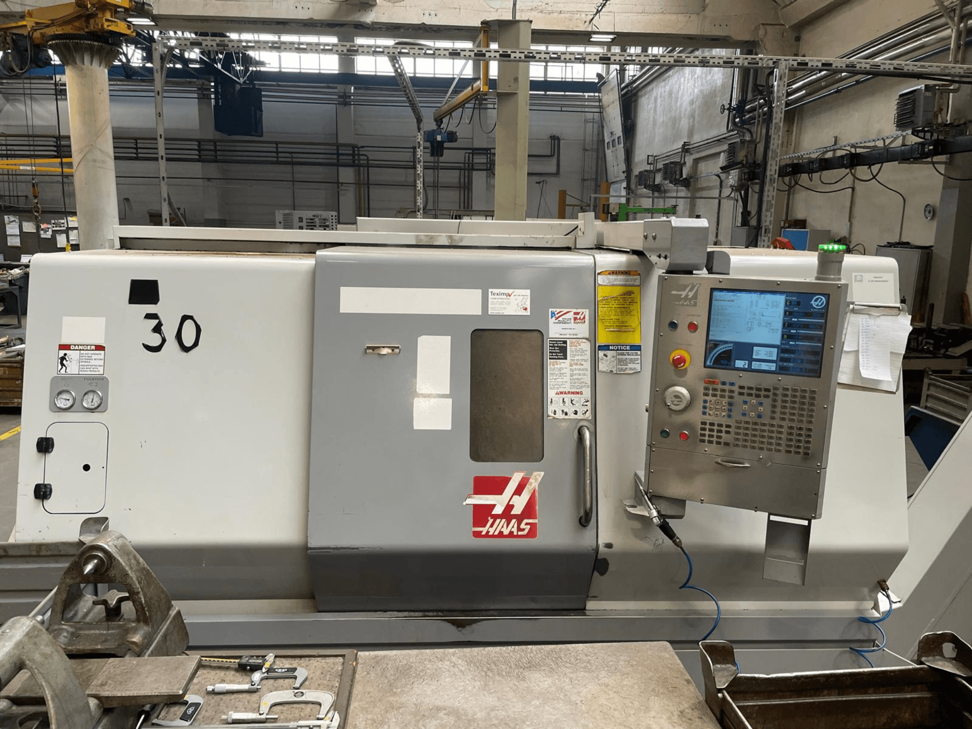 Haas SL-30THE horizontal turning machine front view, featuring digital control panel, hazard labels, and model number 30.