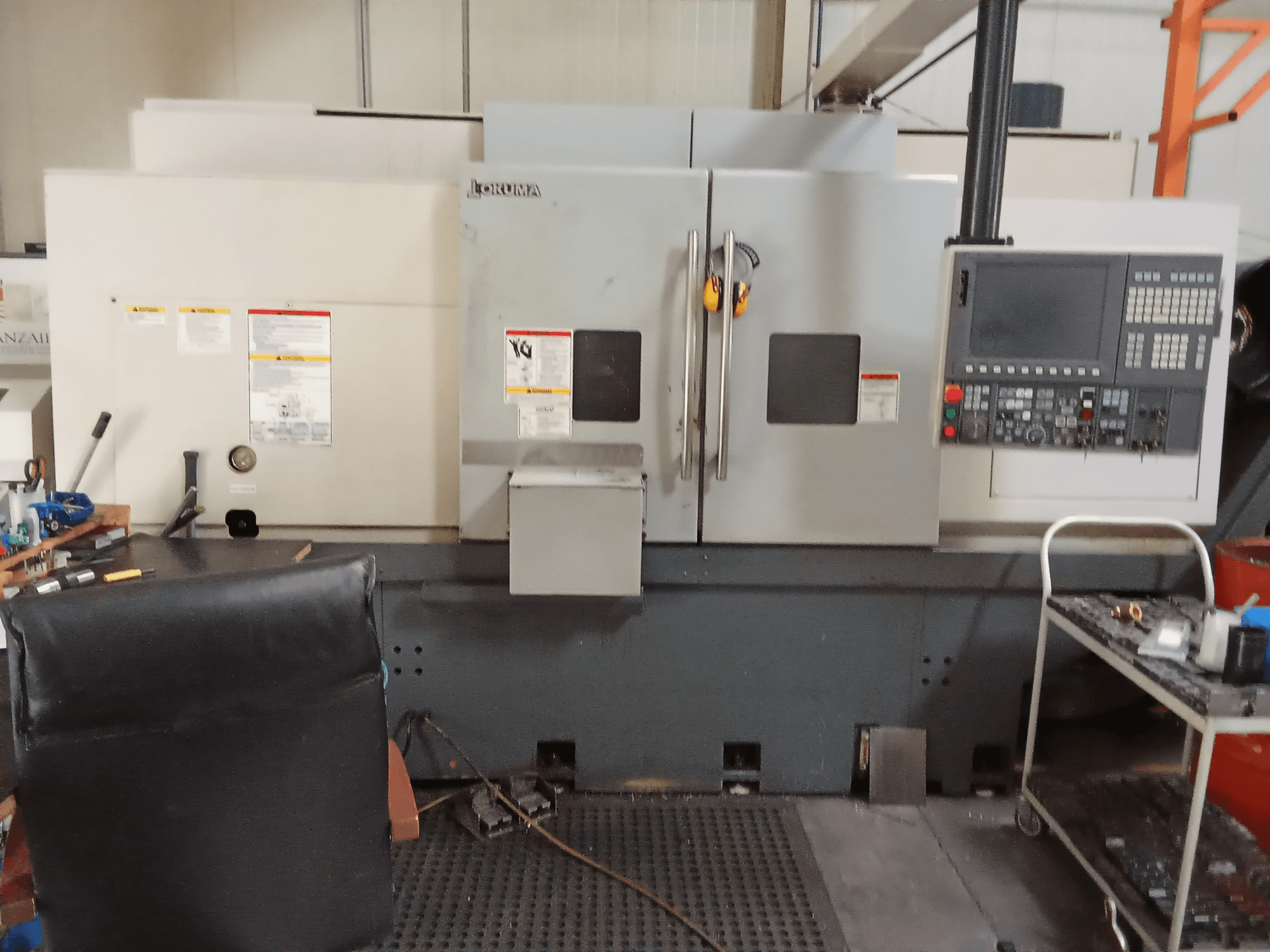 Okuma Genos L300 E-M horizontal turning machine in front view, showcasing control panel and dual doors, set in a workshop environment.