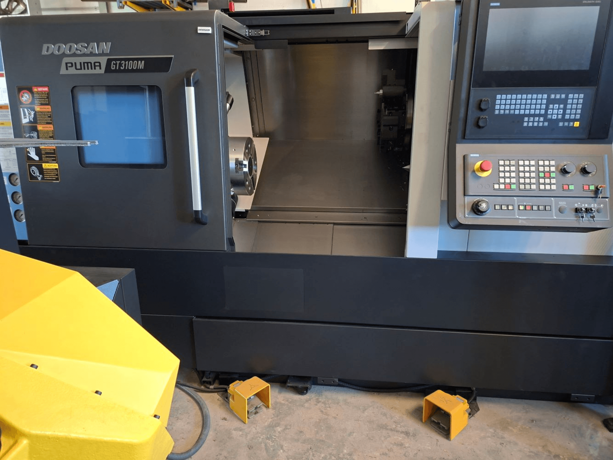 DOOSAN Puma GT 3100 M horizontal turning machine in front view, showcasing control panel, open turret, and interior workspace.