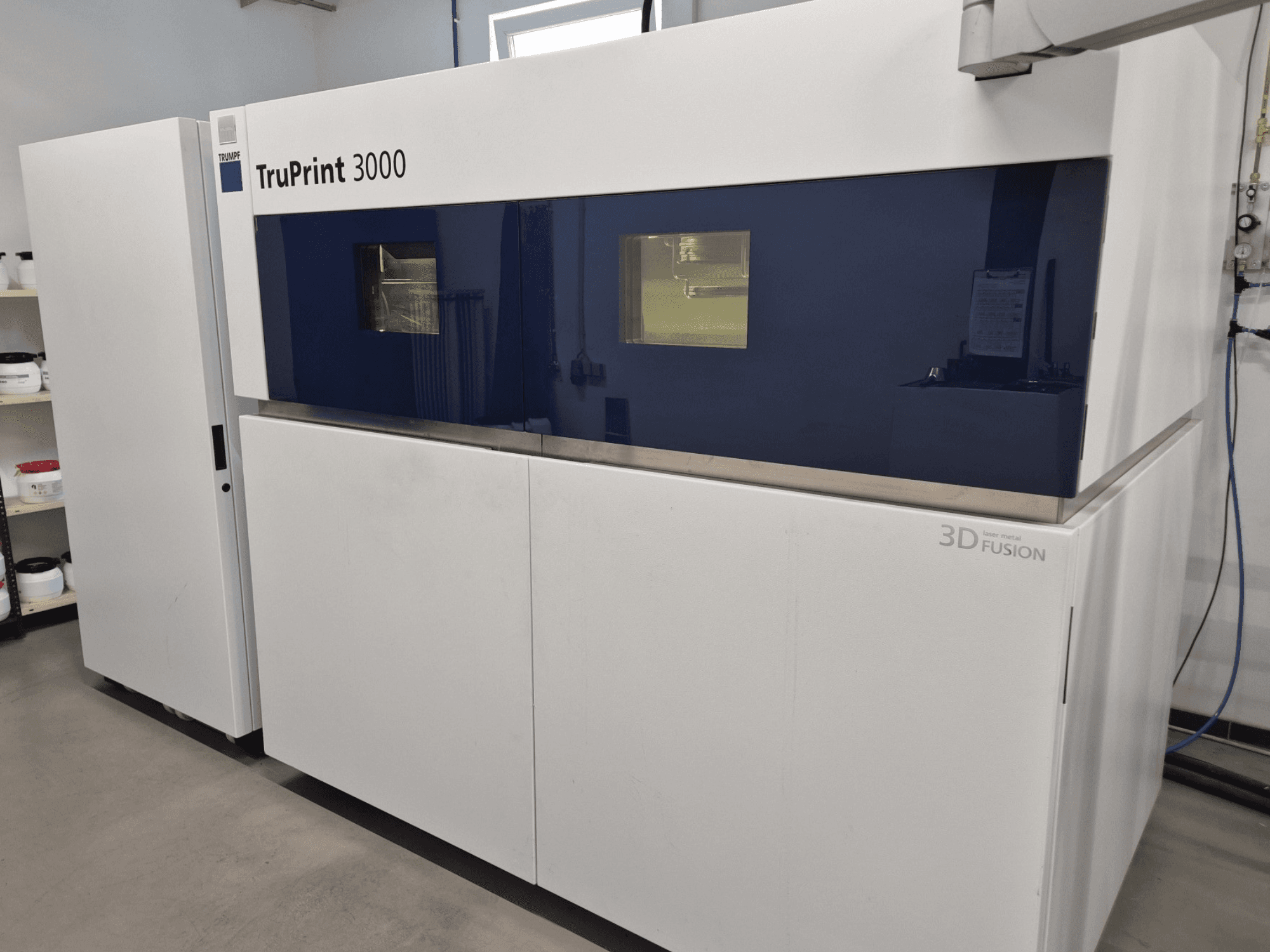 TruPrint 3000 metal 3D printer in front view, featuring a blue-paneled design and laser fusion technology.