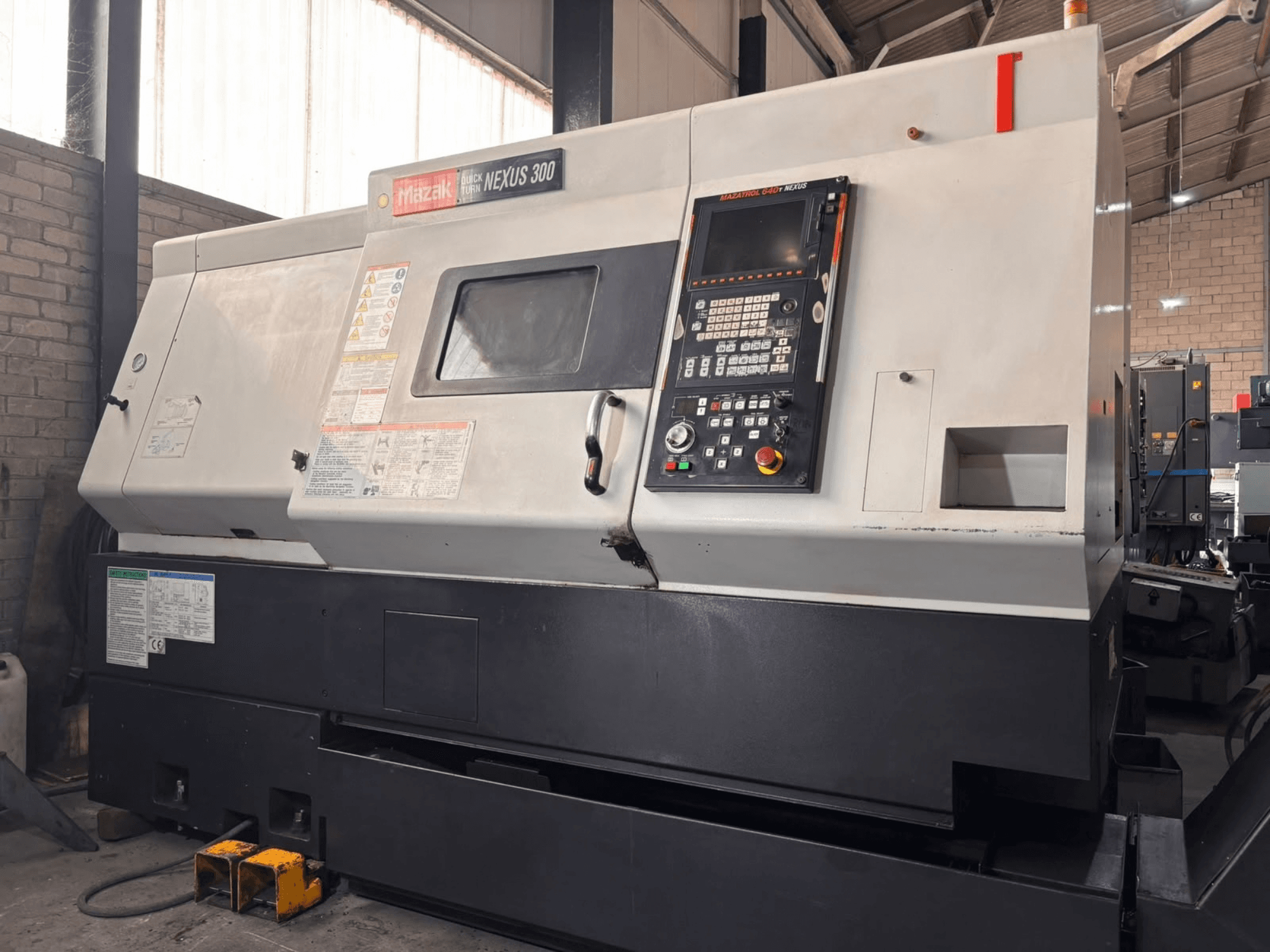 Mazak QT NEXUS 300 horizontal turning machine, side view showing control panel and operation indicators in a workshop setting.