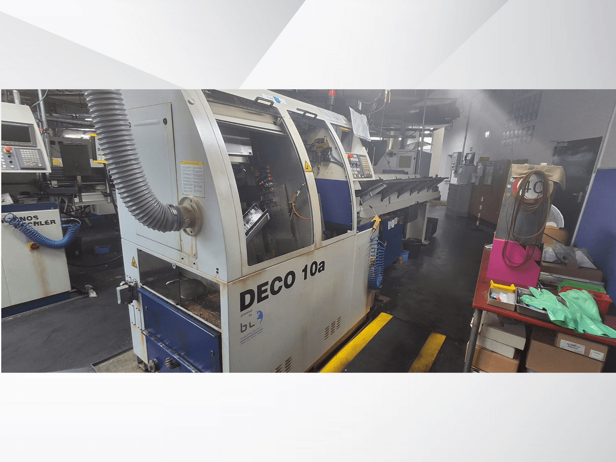 DECO 10a CNC machine in a workshop, front view; features a control panel and dust extraction system, with workbench nearby.