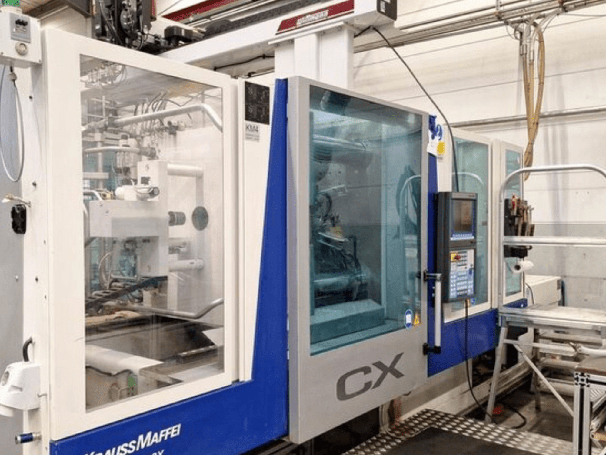 Krauss Maffei 300-1400 CX hydraulic injection moulding machine, side view, showcasing control panel and transparent casing.