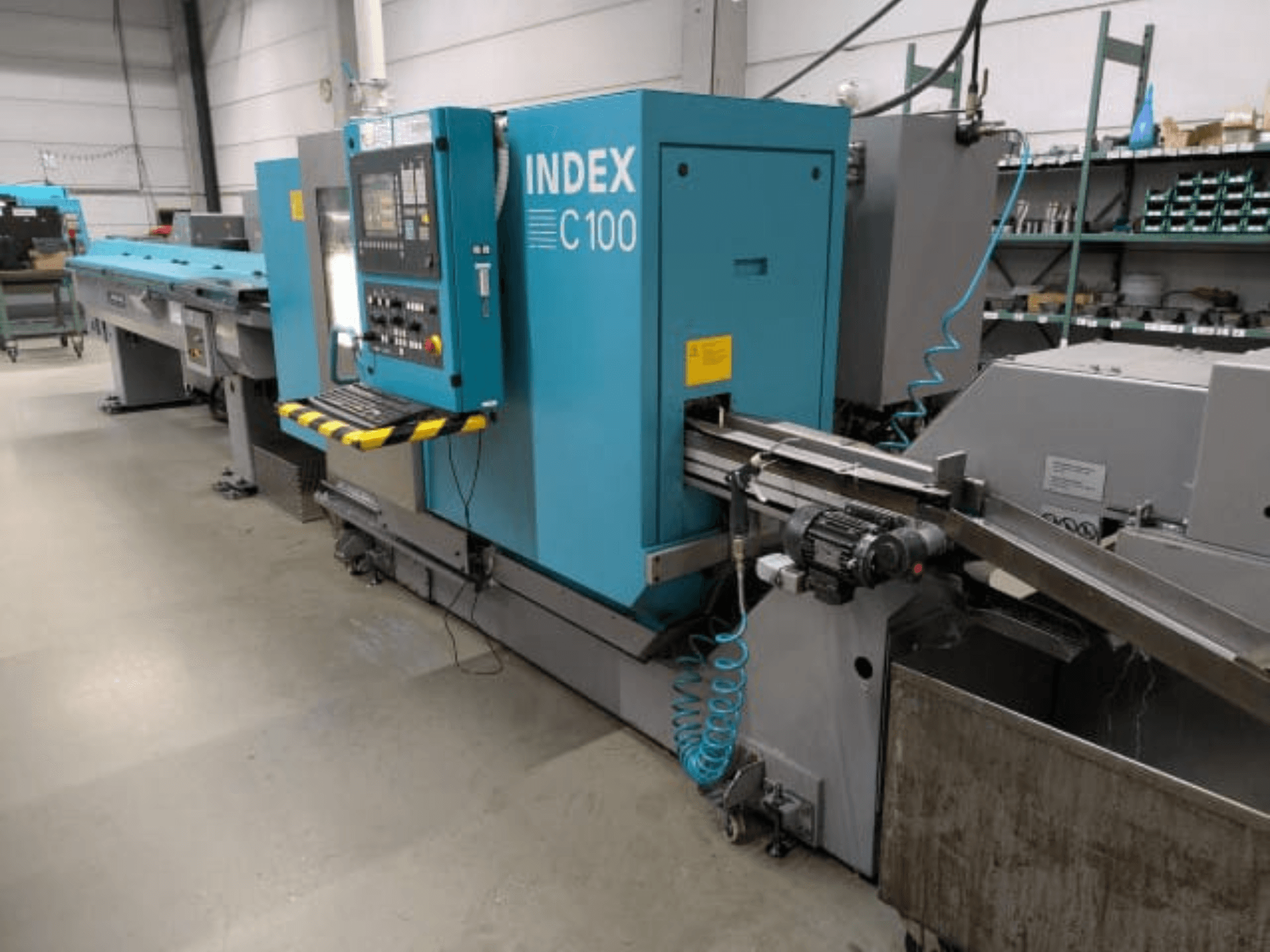Index C100 horizontal turning machine, side view; features a control panel, feed system, and metal chip collection bin.