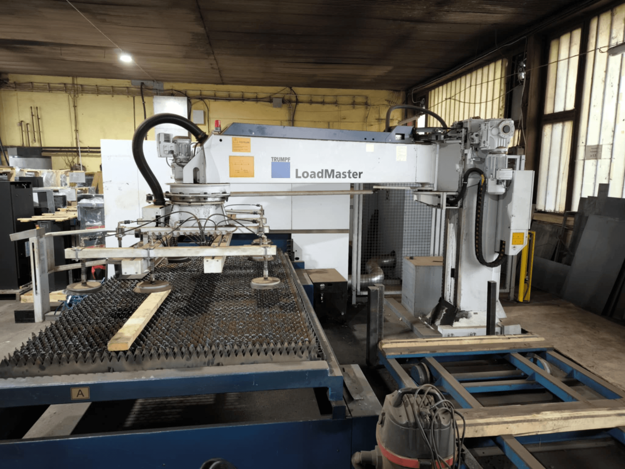 TRUMPF TRULASER 3030 FIBER cutting machine, front view, showcasing LoadMaster system and positioned on a grated work table.