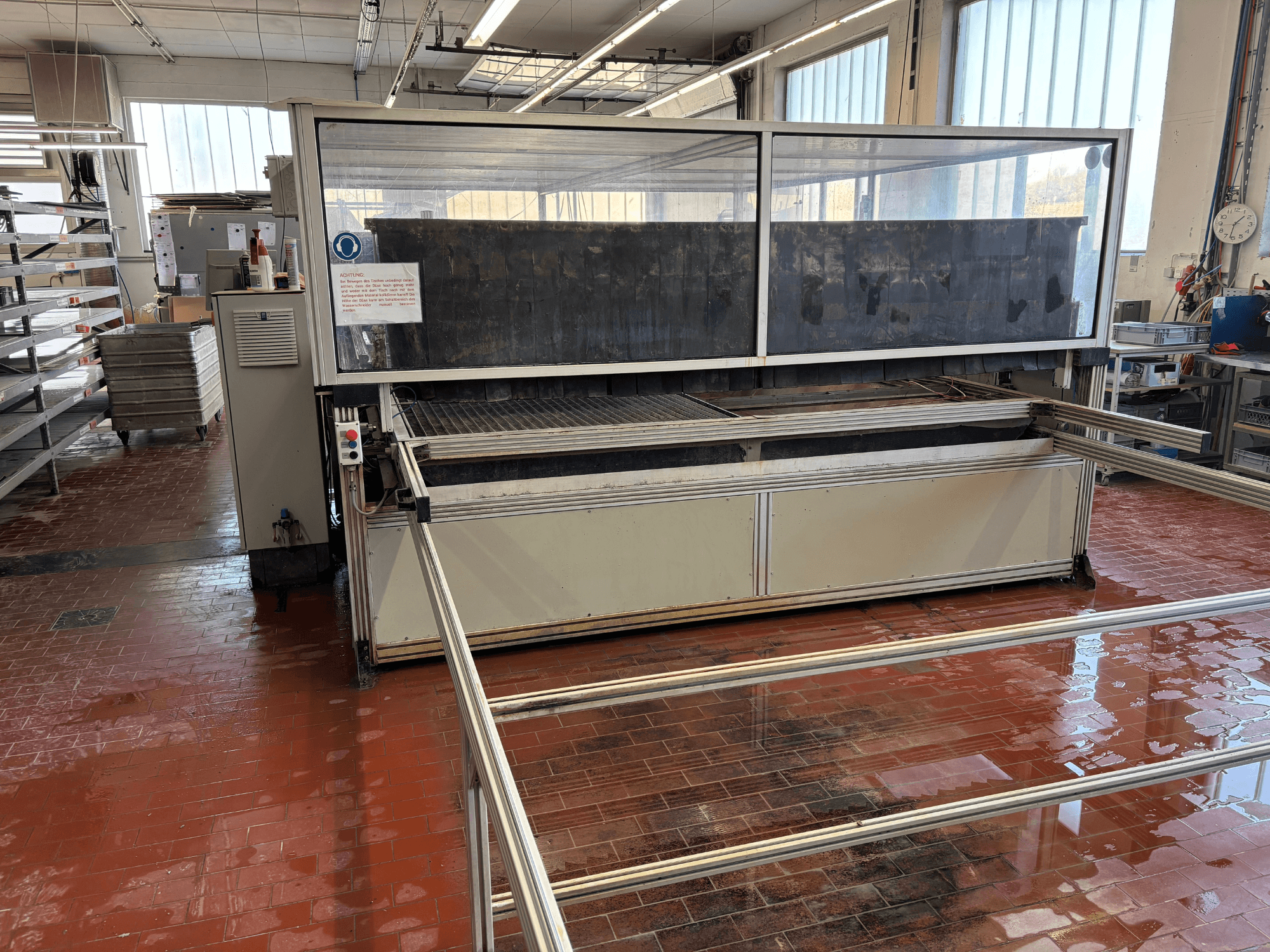 Waterjet cutting machine EXPERT SYSTEMTECHNIK cutExpert variojet in a workshop, front view, featuring a large transparent cover.