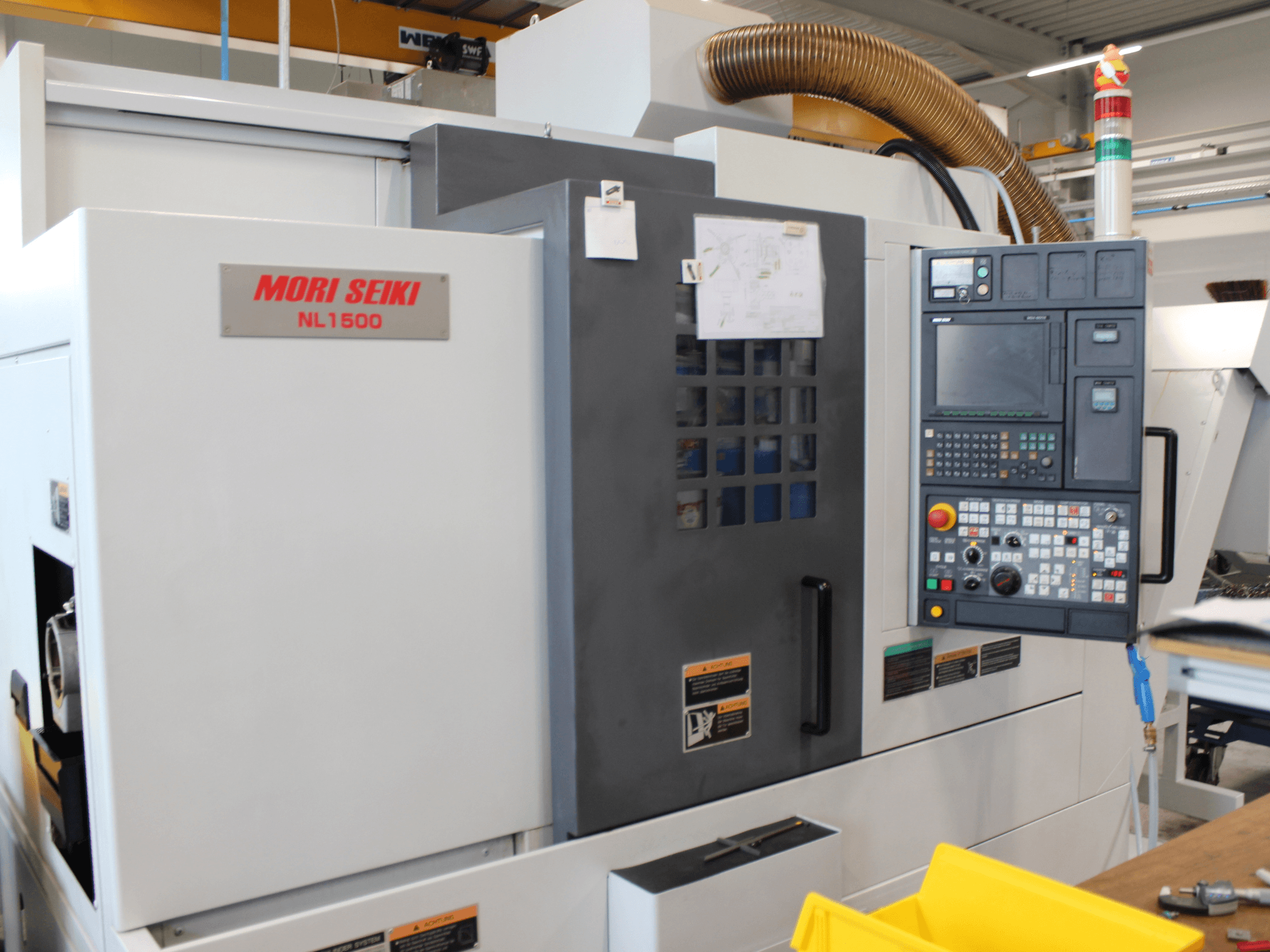 MORI SEIKI NL 1500 SY turn-mill centre in side view, featuring control panel, operational safety labels, and cooling system.