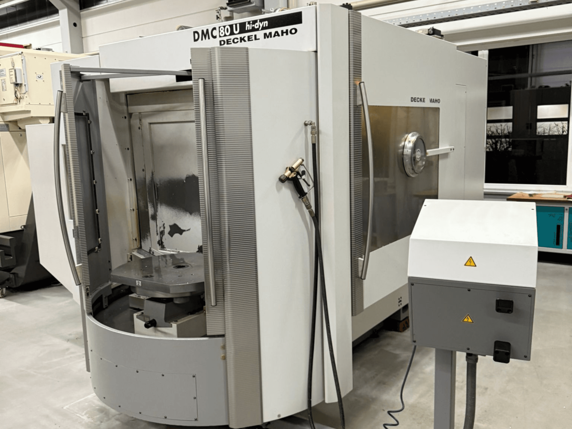Front view of a Deckel Maho DMC 80 U high-speed CNC milling machine, featuring an open access door and control panel on the side.