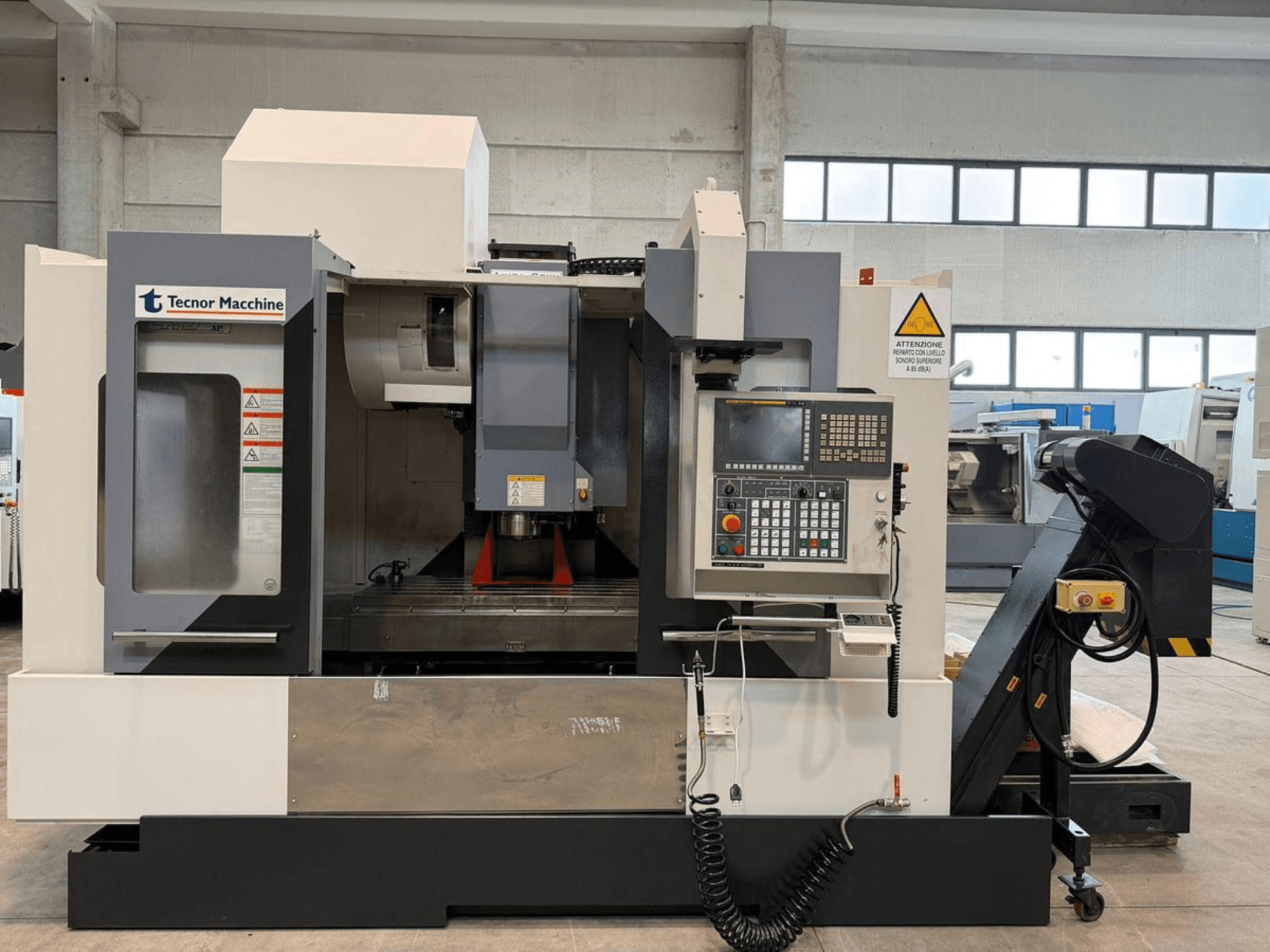 Tecnor Machine CNC milling machine, front view, features control panel with buttons, warning labels, and tool holder.
