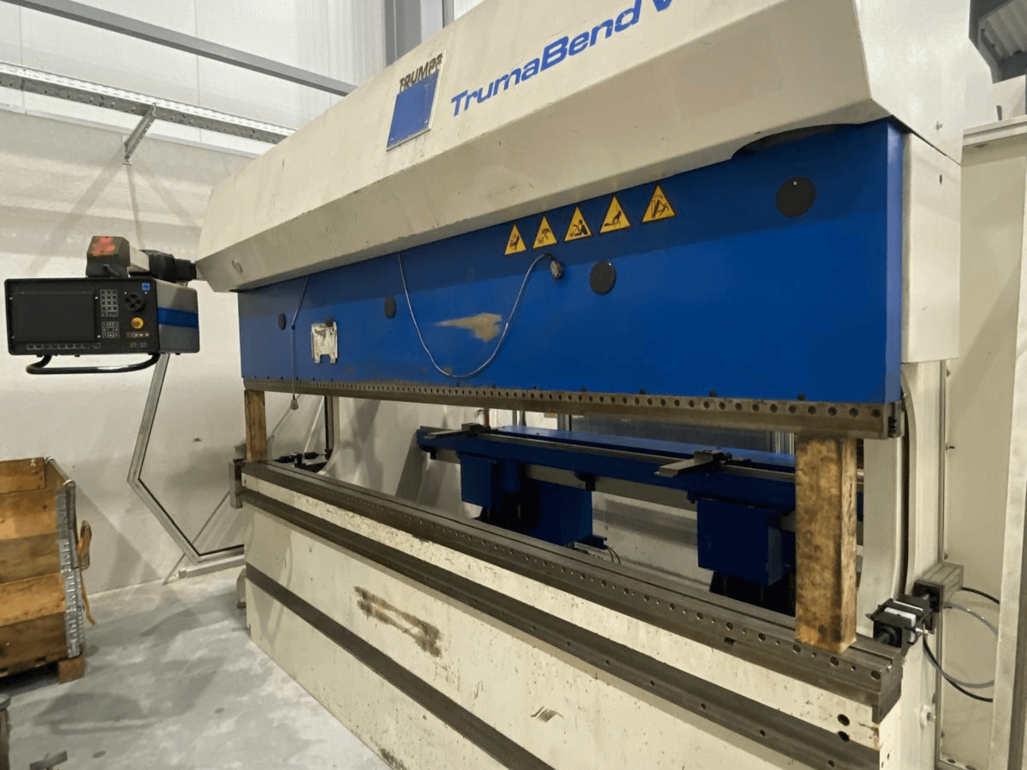 TRUMPF Trumabend V130 press brake, front view, with control panel, blue elements, and safety warning labels visible.