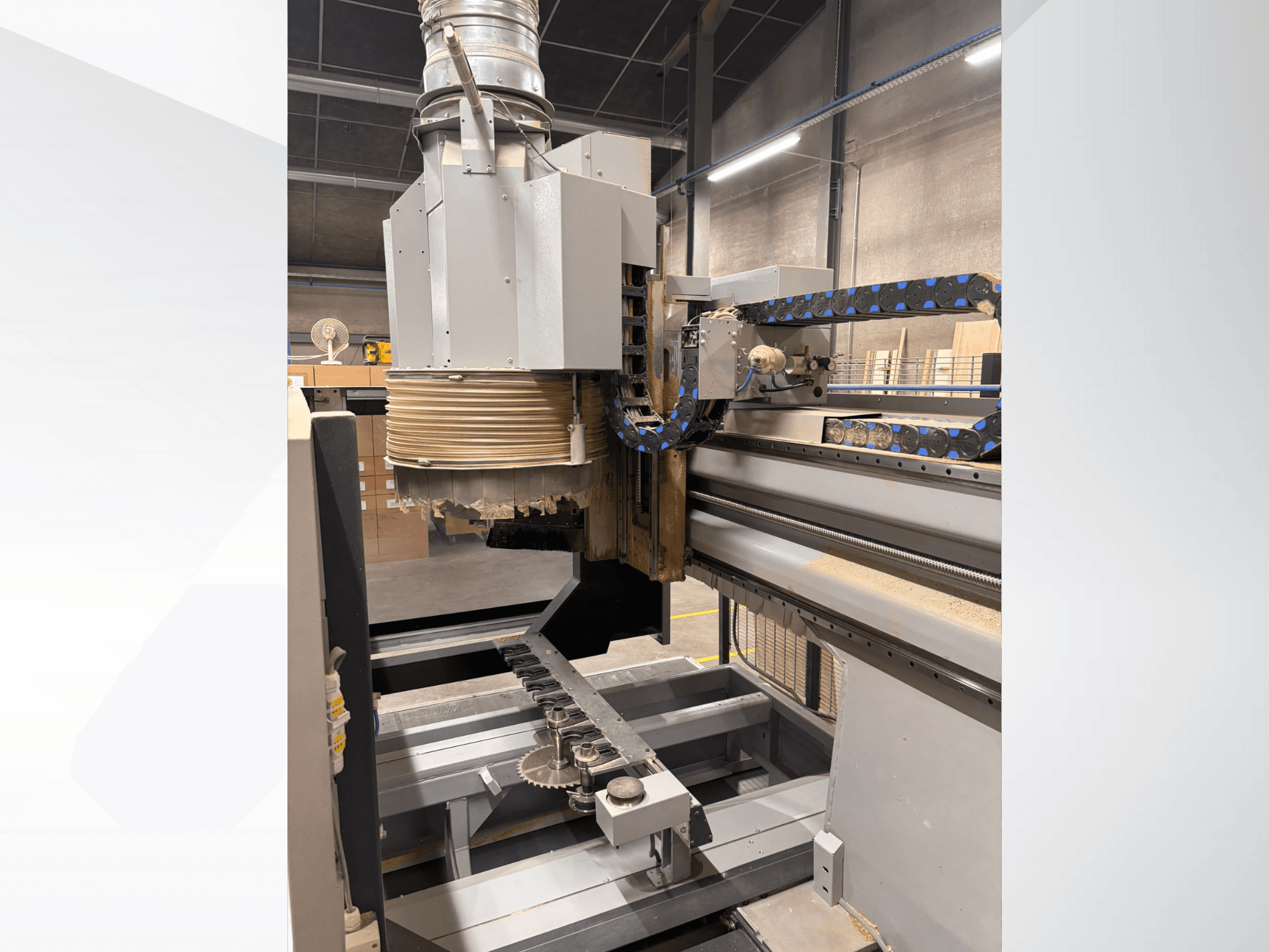 CNC router machine with a large spindle and conveyor, side view, displaying wood cutting tools and machinery components.