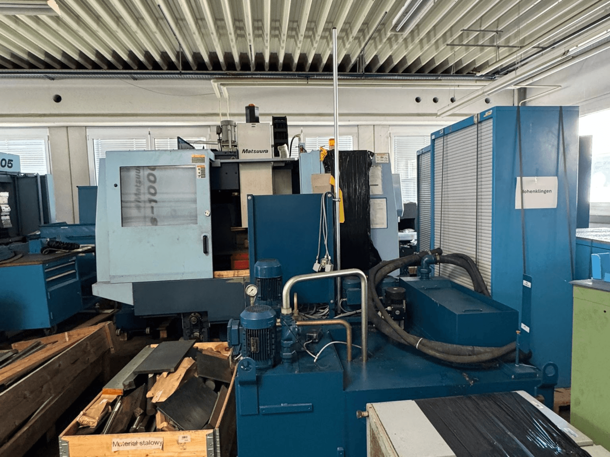 Front view of Matsuura Vplus 1000/40 vertical machining center, showing controls, motors, and surrounding workshop environment.