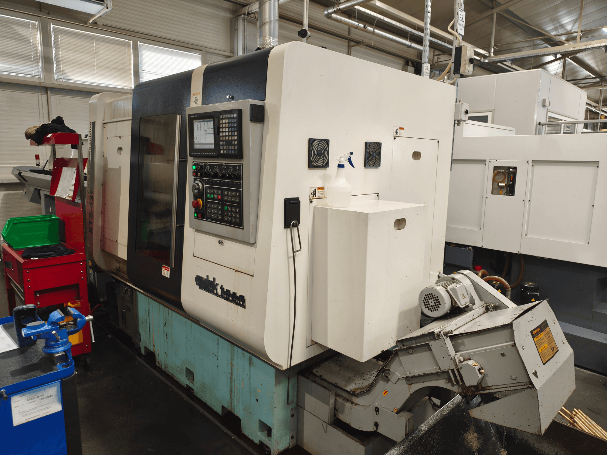 Front view of Quick-Tech XTS-42 horizontal turning machine, featuring a control panel and coolant reservoir.