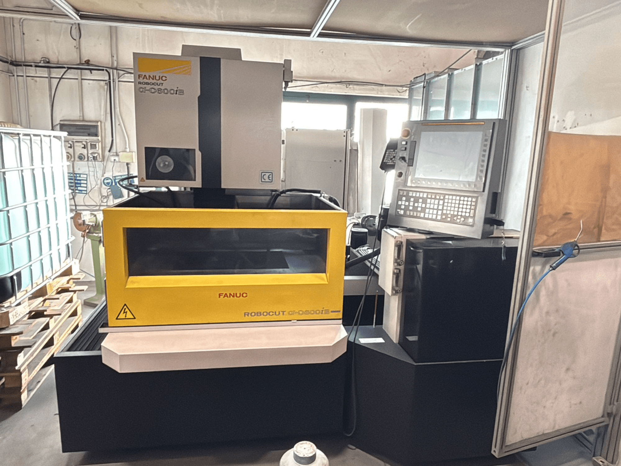 Front view of a FANUC Robocut α-0iE CNC machine with a yellow casing, showcasing control panel and display.