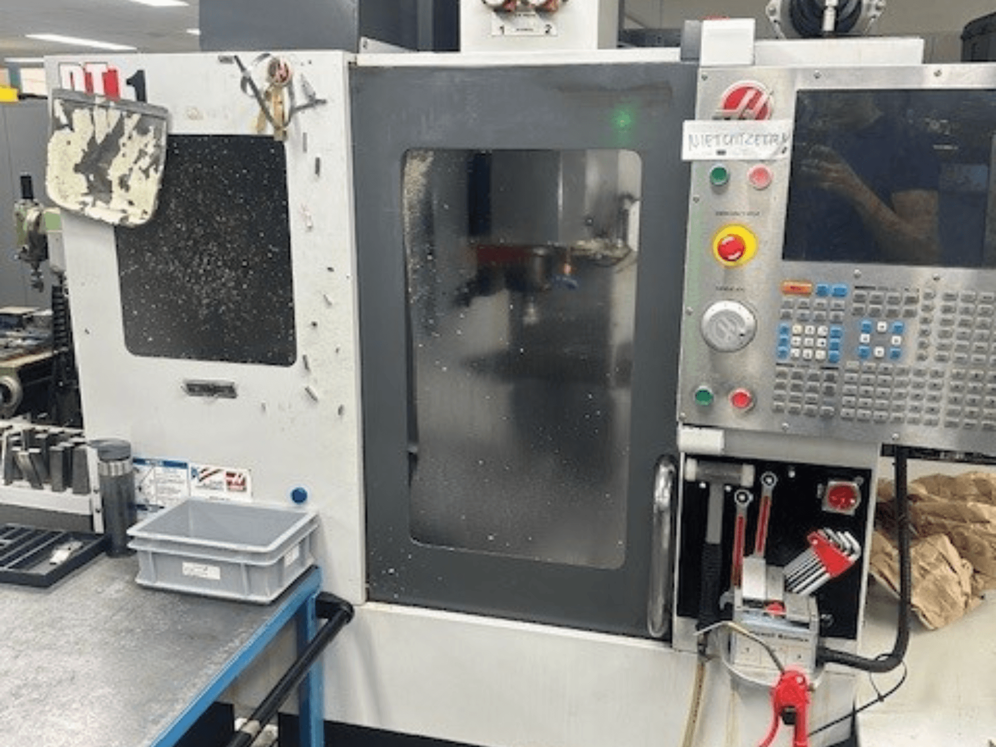 Haas DT-1 Vertical Machining Centre, front view with control panel, visible dirt, and tool tray on the workbench.
