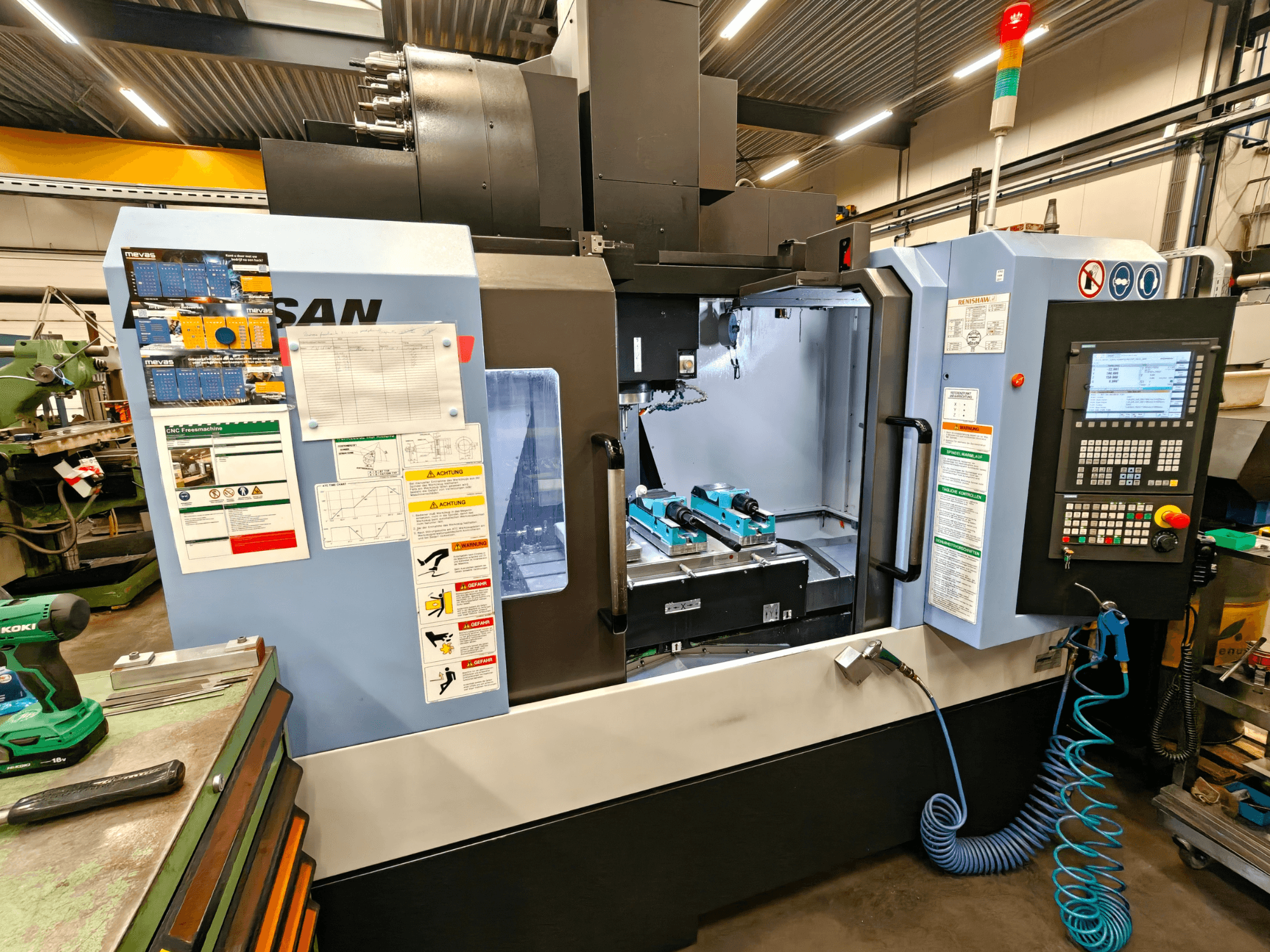 DOOSAN DNM 400 II vertical machining center in a workshop, featuring controls, tool holders, and safety signage, front view.