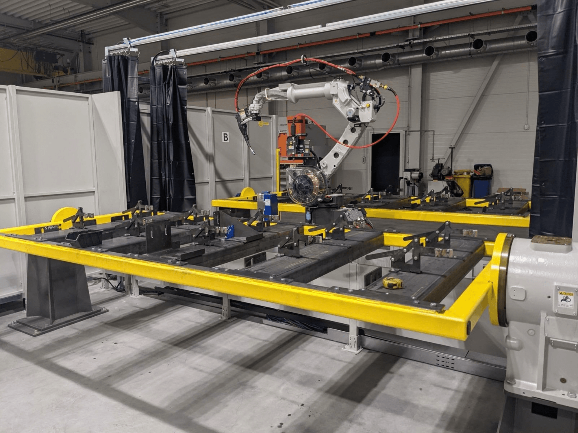 Front view of PANASONIC TAWERS TM-2000WG3 robot arm positioned above a yellow worktable with metal parts for assembly.