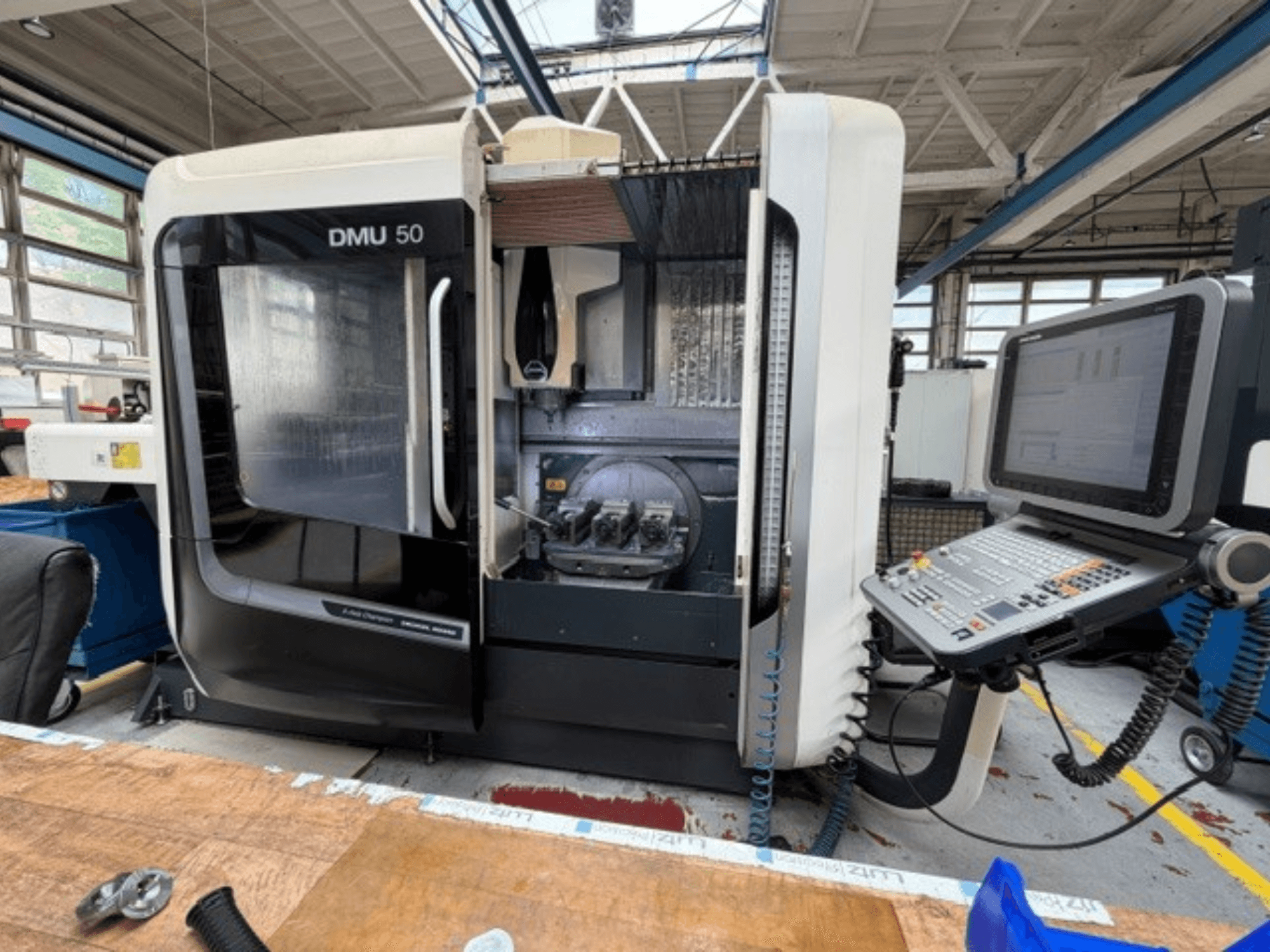DMG MORI DMU 50 3rd gen vertical machining center shown from the front, with open door, CNC control panel visible, and workspace inside.