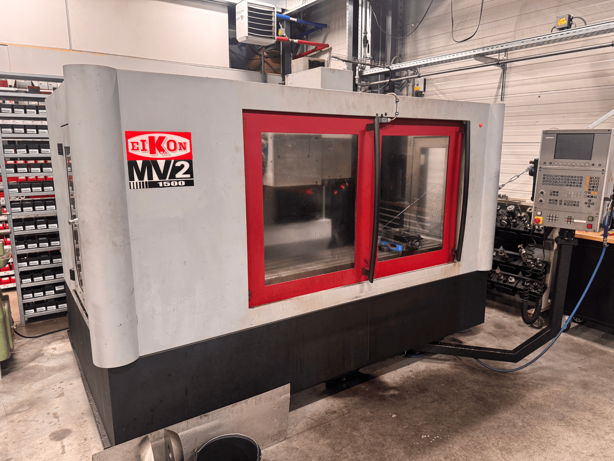Eikon MV2 vertical machining center in a workshop, front view with red accents and control panel visible on the side.