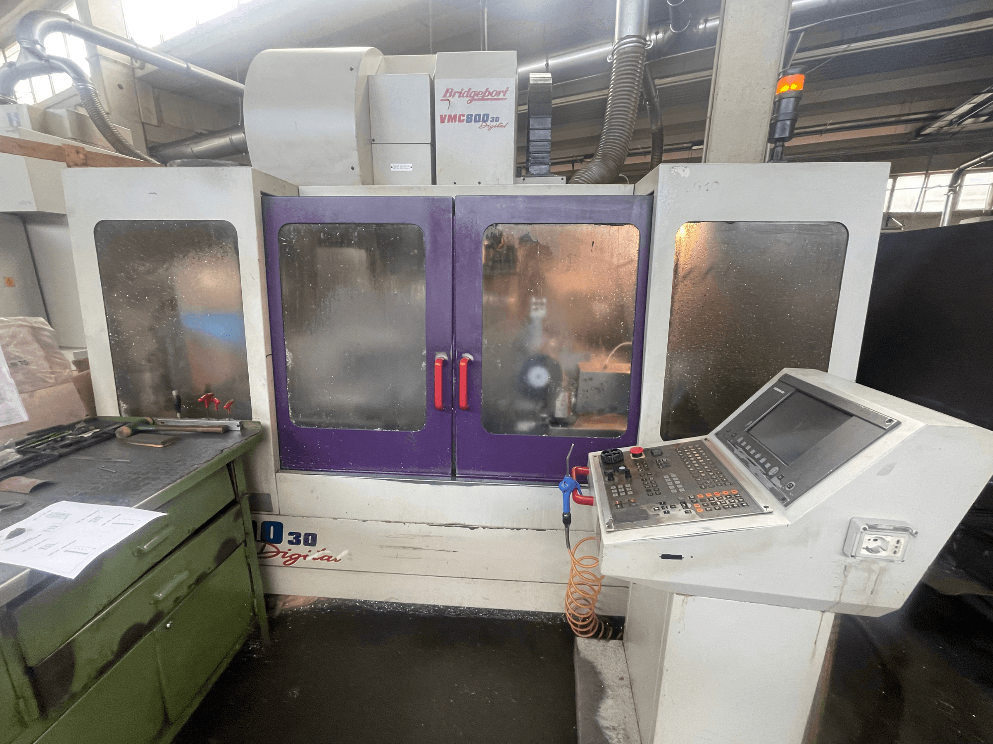 Bridgeport VMC 800/30 Vertical Machining Centre, front view, showcasing control panel and purple doors, tools on adjacent surface.