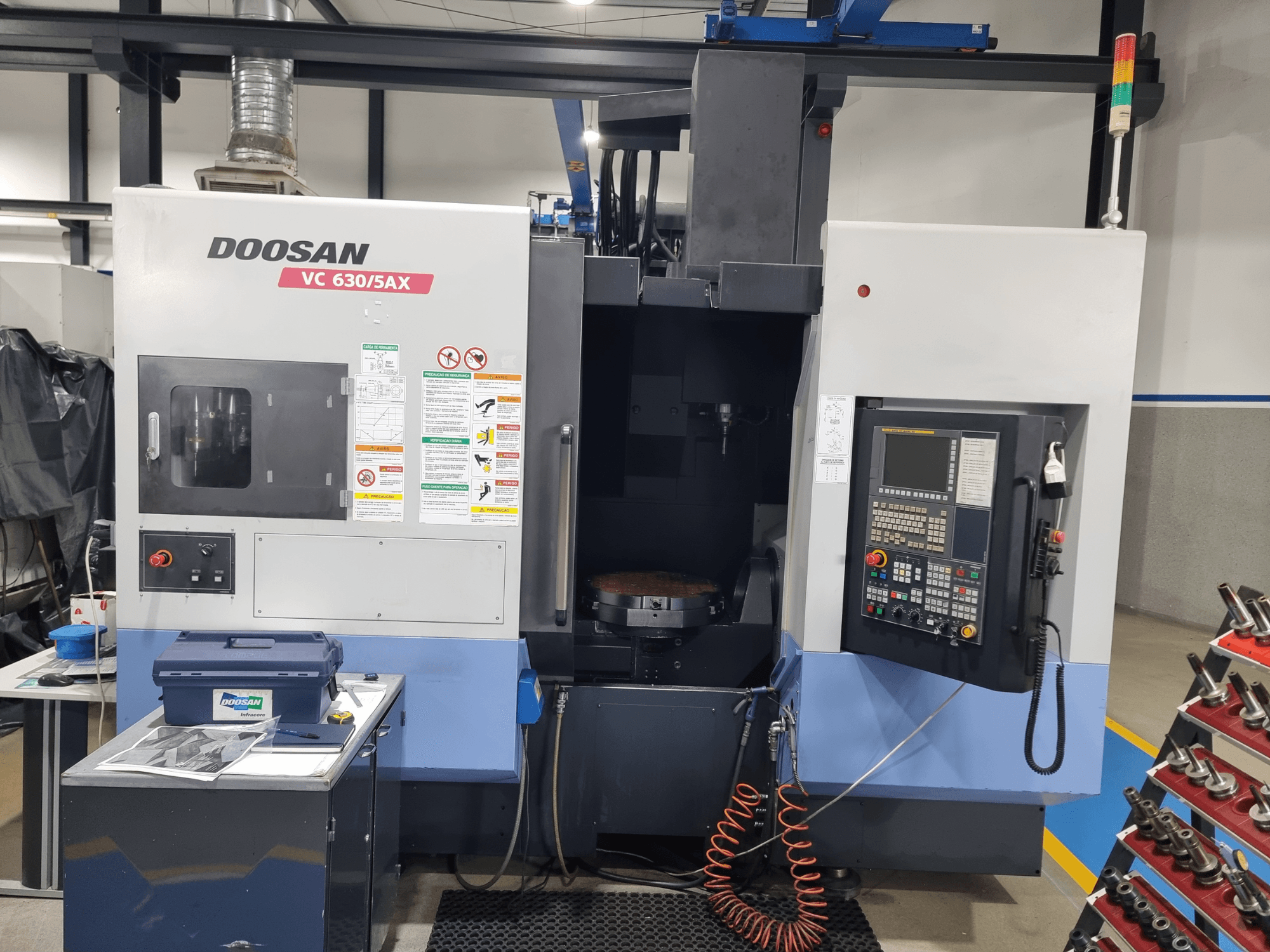 DOOSAN VC 630/5AX universal machining center, front view showcasing control panel, cutting area, and safety features.