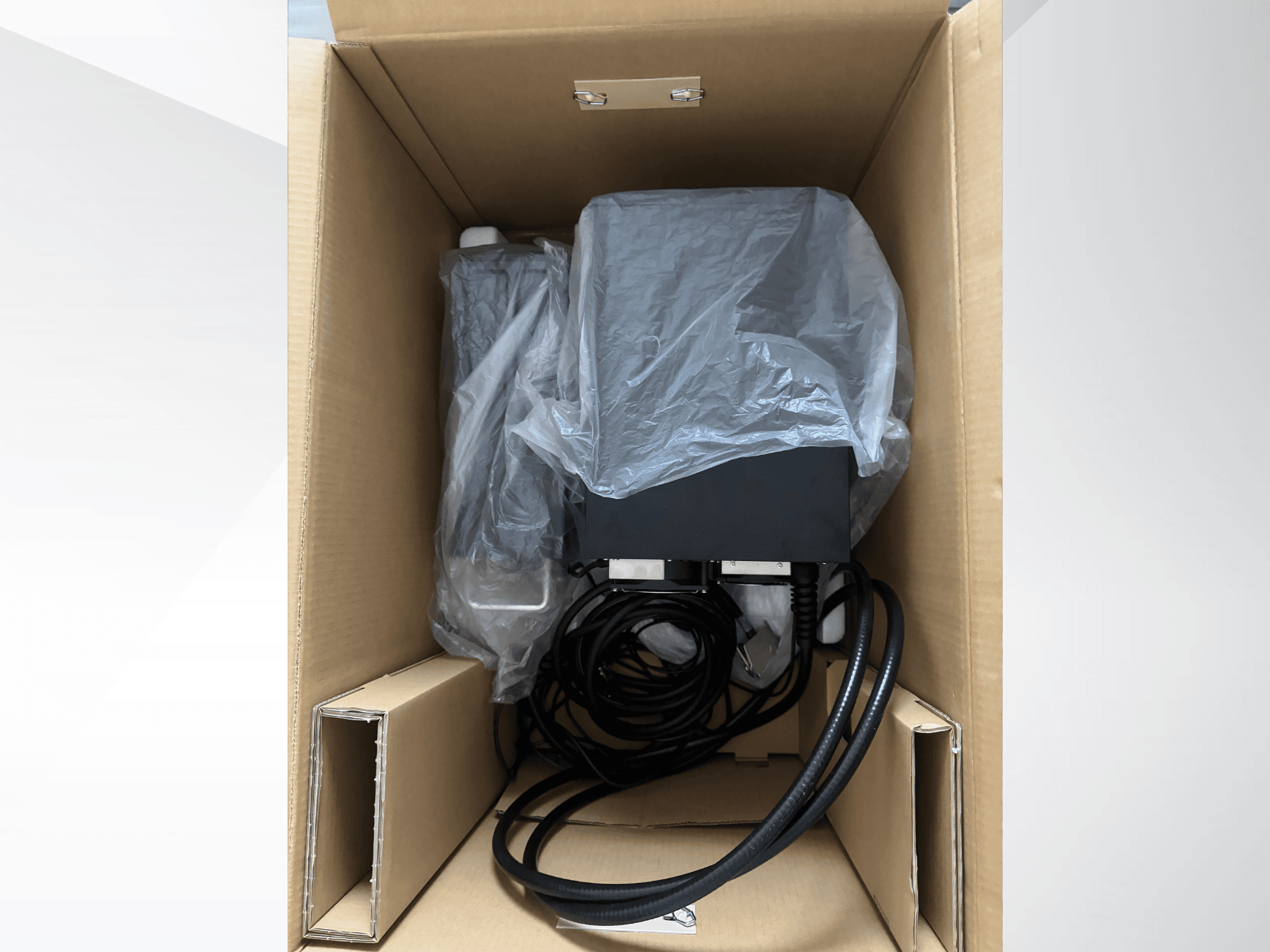 KEYENCE MD-X2500A Laser Marking Machine in cardboard box, partially covered with plastic, showing cables and components.
