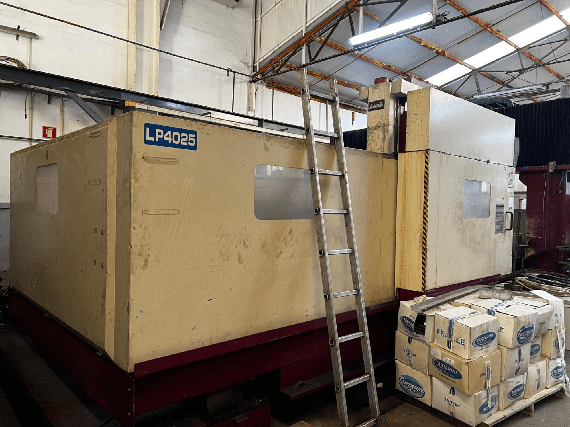Gantry milling machine AWEA LP4025 in an industrial setting, side view showing the large machinery and storage boxes.