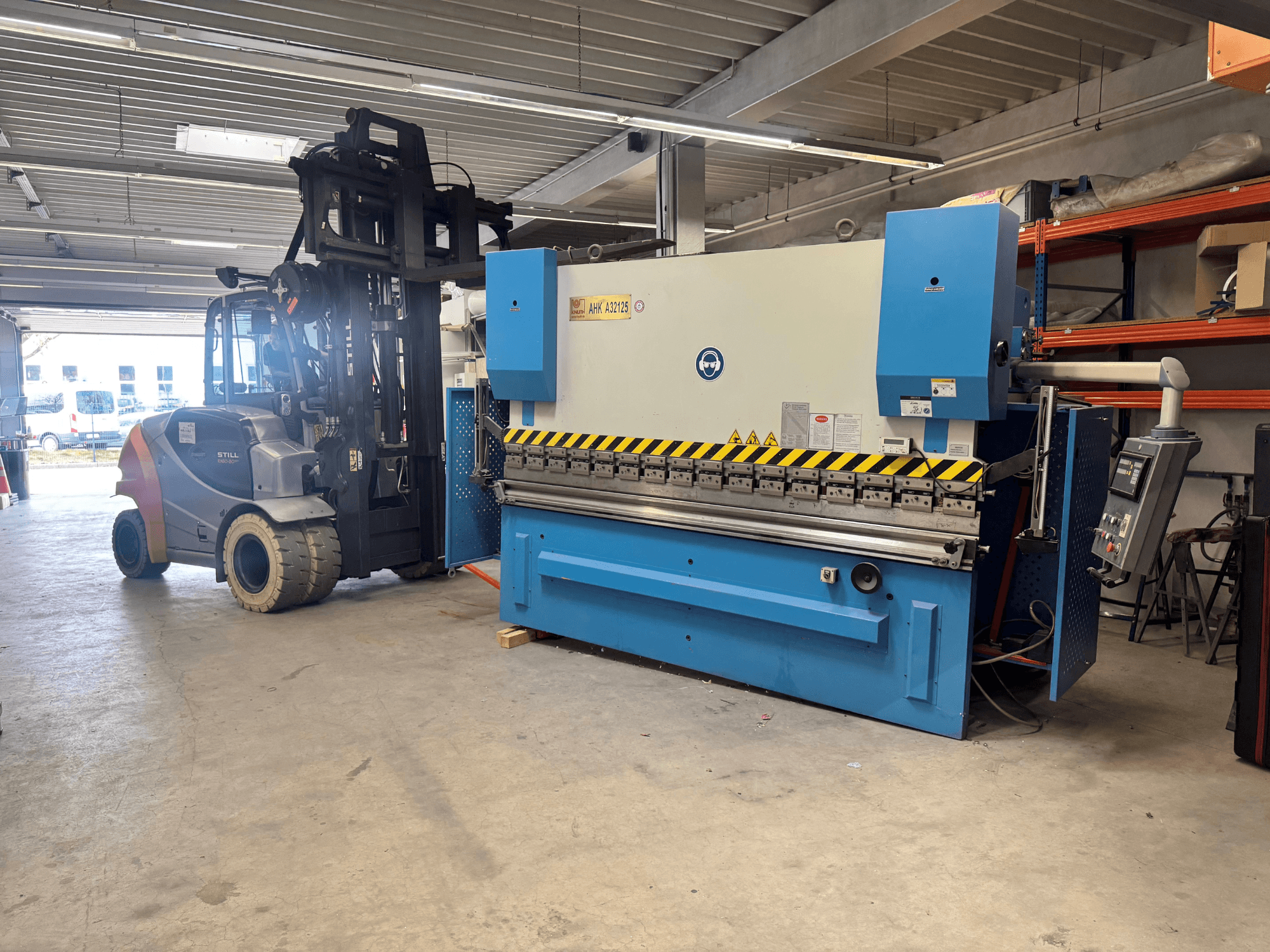 Hydraulic press KNUTH AHK A 32125 in a workshop, side view showcasing control panel and safety features.