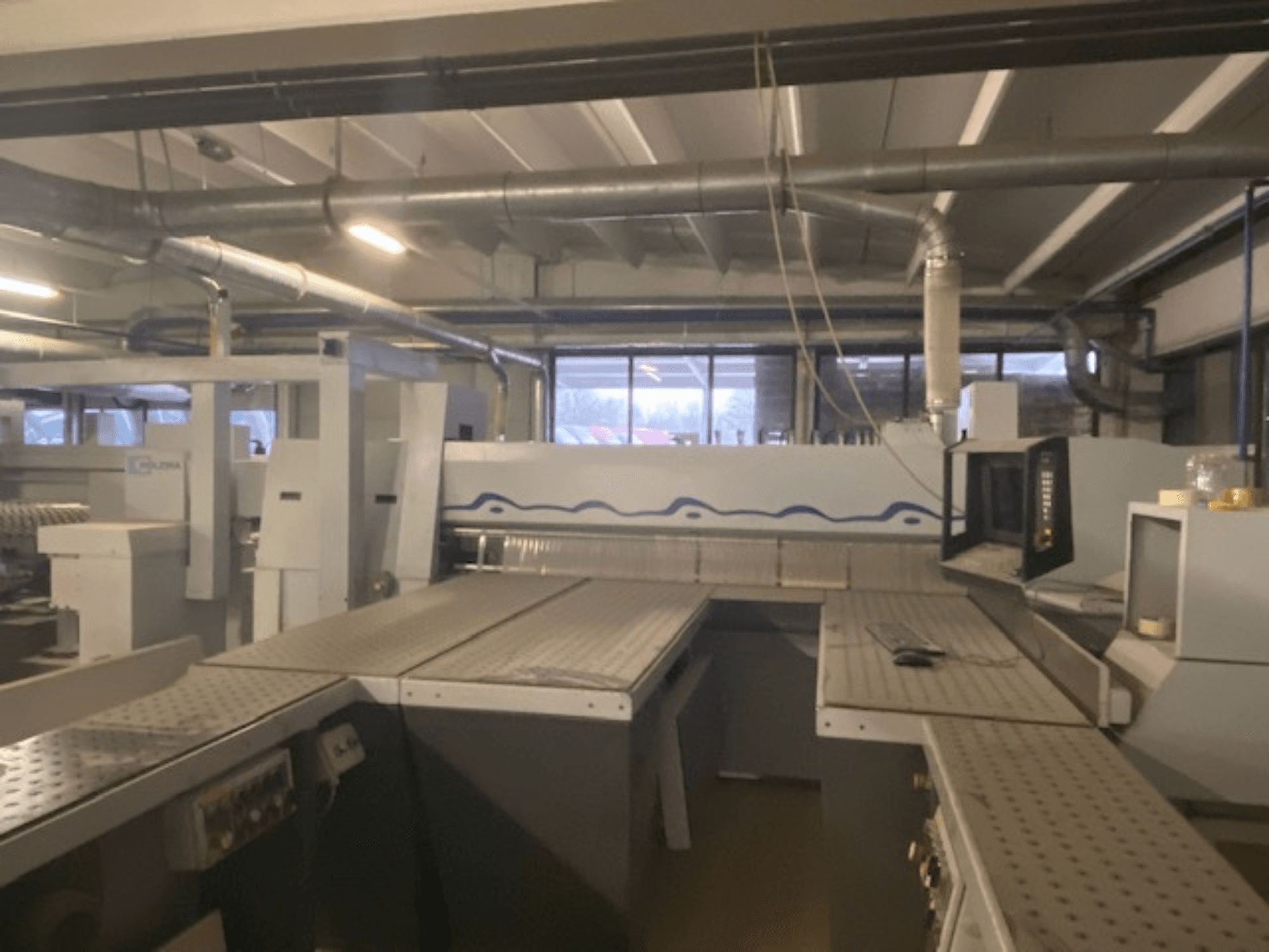 Industrial workspace featuring a machinery setup with control panel, viewed from an elevated front angle.