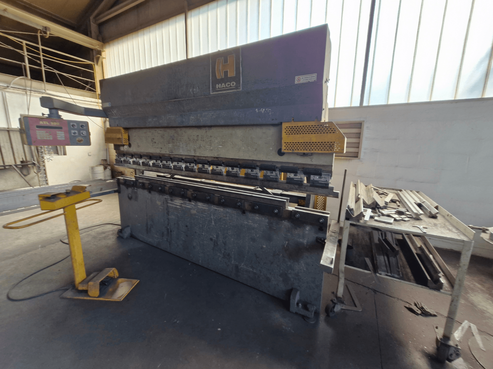 HACO PPM 30135 b press brake in a workshop, front view showing control panel and scrap metal on a table beside it.