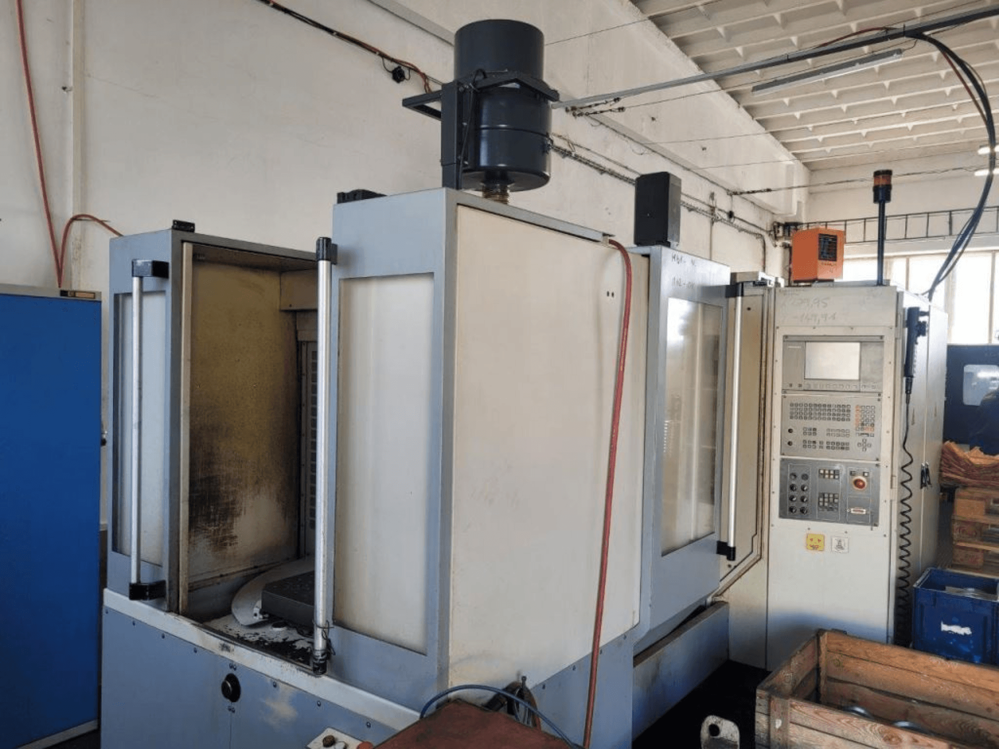 Industrial CNC milling machine with control panel, side view, showing enclosure and visible dirt on surfaces.