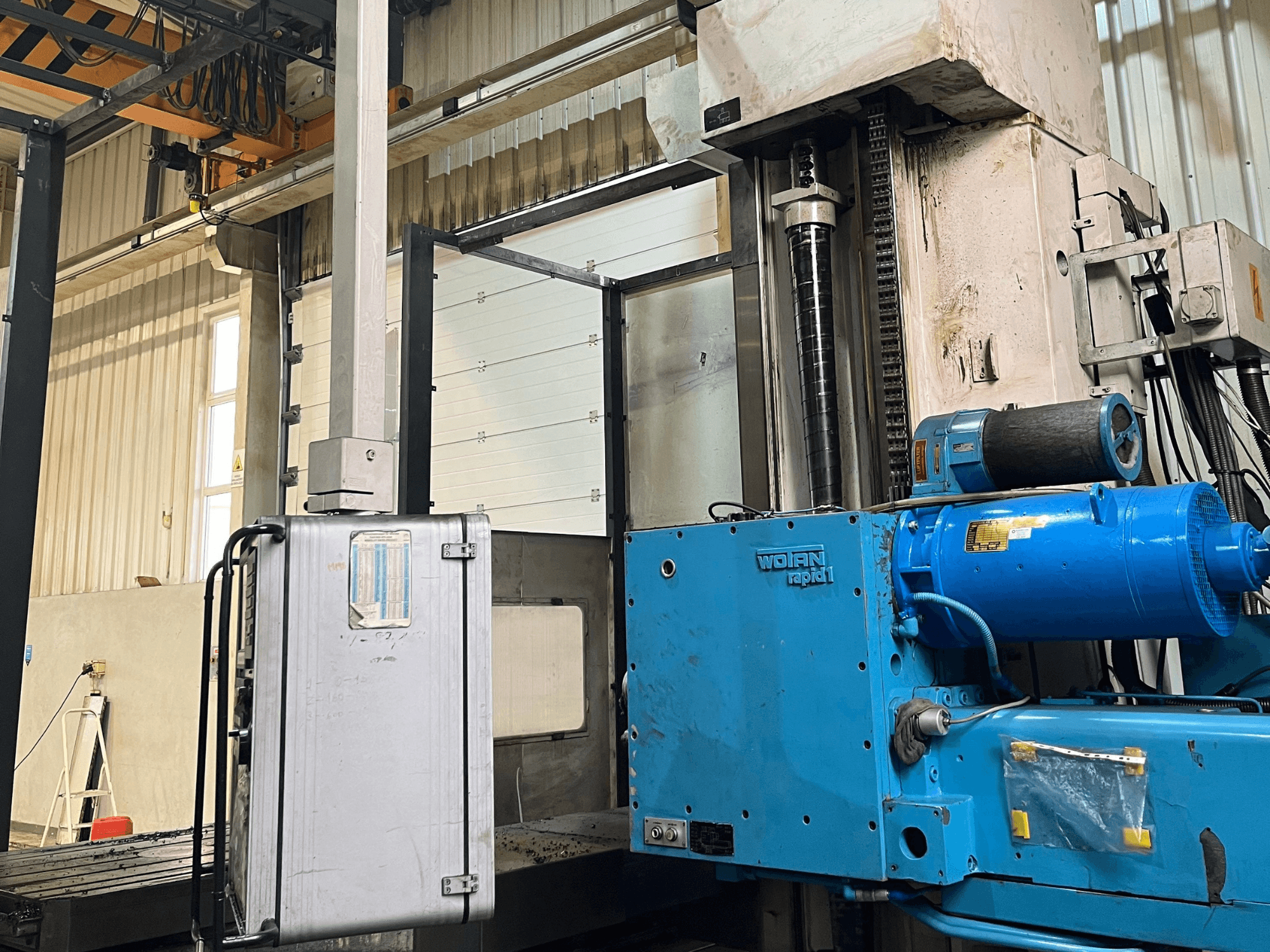 Boring machine WOTAN Rapid 1 in blue, side view, showing motor, controls, and vertical column in a workshop setting.